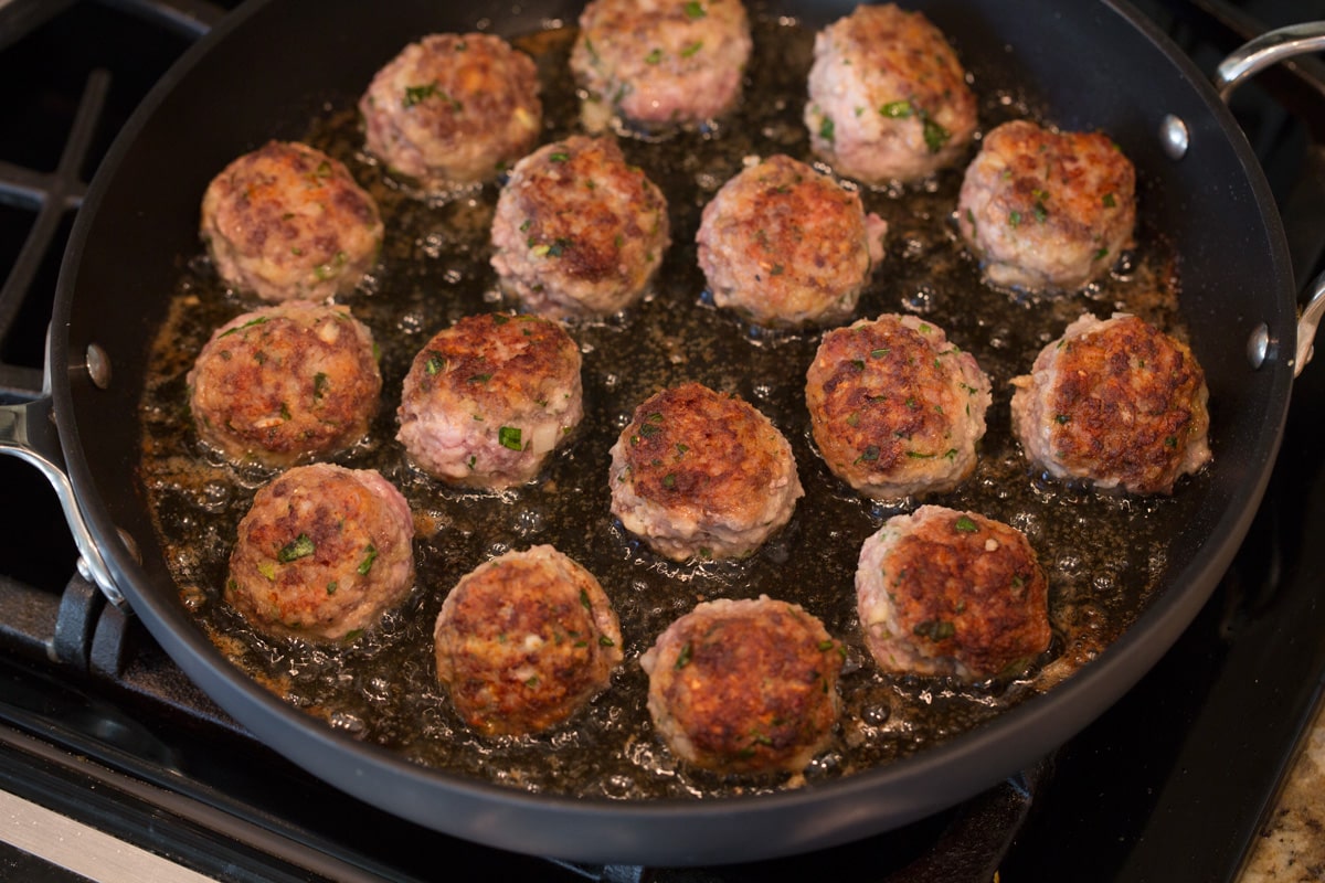 BEST MEATBALLS - these are so flavorful, so tender and packed with fresh ingredients! Makes the best spaghetti and meatballs ever! #meatballs #spaghetti #italian #dinner #groundbeef #pork #recipe Cooked meatballs in a skillet with olive oil.
