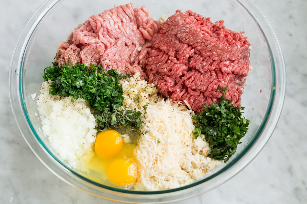 BEST MEATBALLS - these are so flavorful, so tender and packed with fresh ingredients! Makes the best spaghetti and meatballs ever! #meatballs #spaghetti #italian #dinner #groundbeef #pork #recipe Ground beef, ground pork, fresh herbs, parmesan, eggs, onion, garlic and soaked breadcrumbs in a glass mixing bowl.