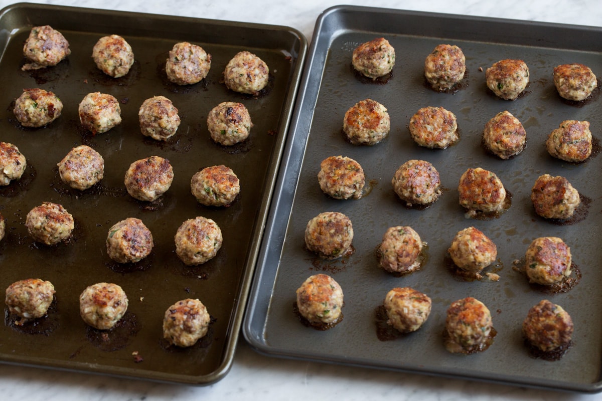 BEST MEATBALLS - these are so flavorful, so tender and packed with fresh ingredients! Makes the best spaghetti and meatballs ever! #meatballs #spaghetti #italian #dinner #groundbeef #pork #recipe Cooked meatballs on two dark baking sheets.