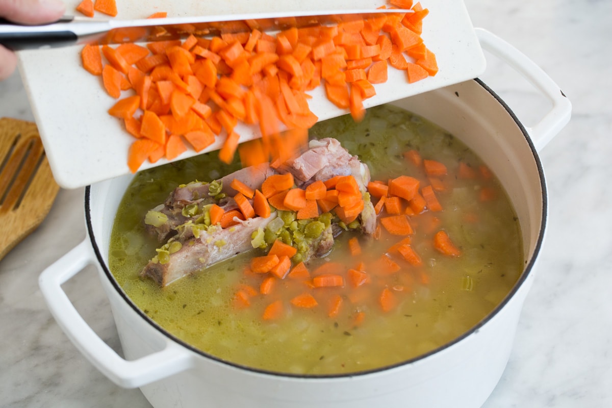 Adding carrots to soup.