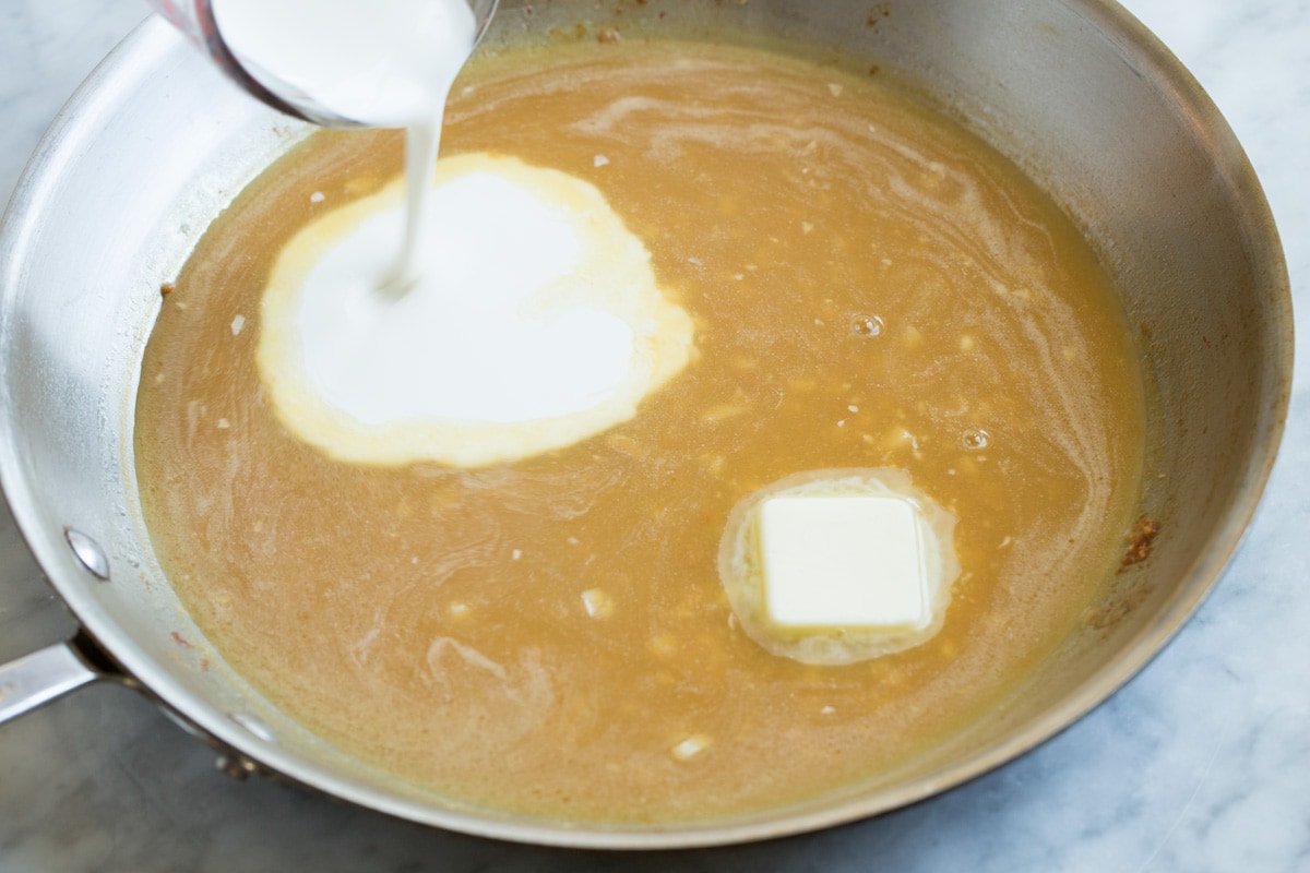 Chicken Piccata Stirring cream and butter into chicken piccata sauce in a skillet.