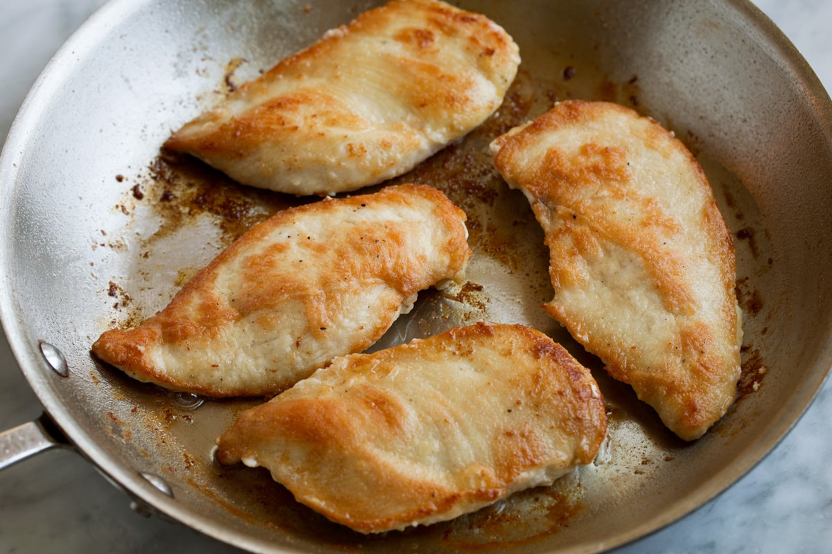 Chicken Piccata Four fully cooked chicken cutlets in a skillet.