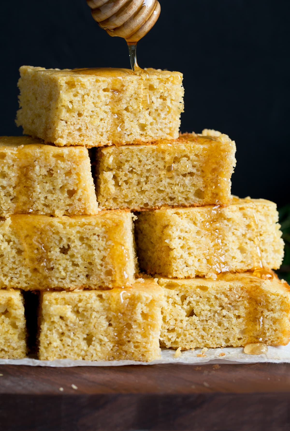 The BEST Cornbread recipe! Soft, moist, fluffy, tender and perfectly delicious! The only cornbread recipe you'll ever need! #cornbread #bread #sidedish #thanksgiving #recipe Drizzling honey on a pyramid of homemade cornbread