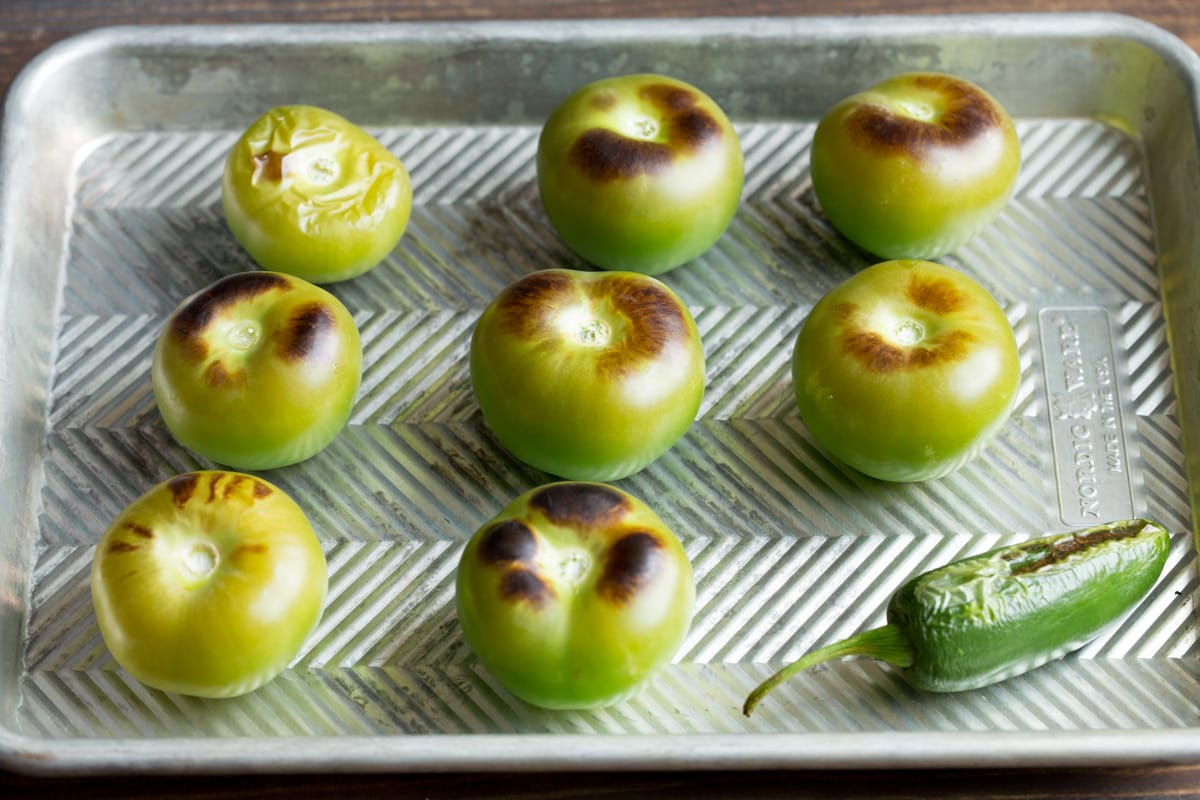 Salsa verde Roasted tomatillos and jalapeno on a baking sheet.