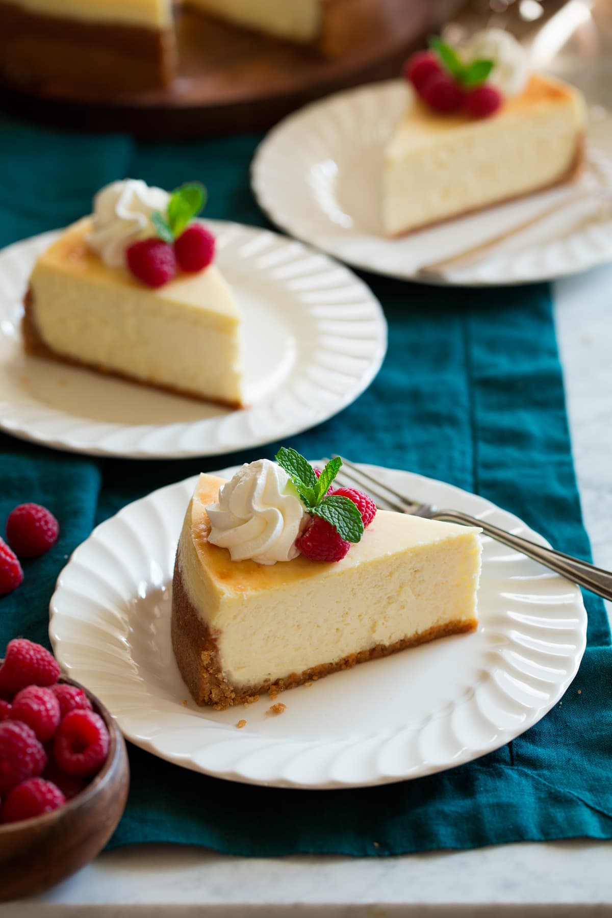 The BEST Cheesecake Recipe! Three slices of cheesecake on dessert plates.