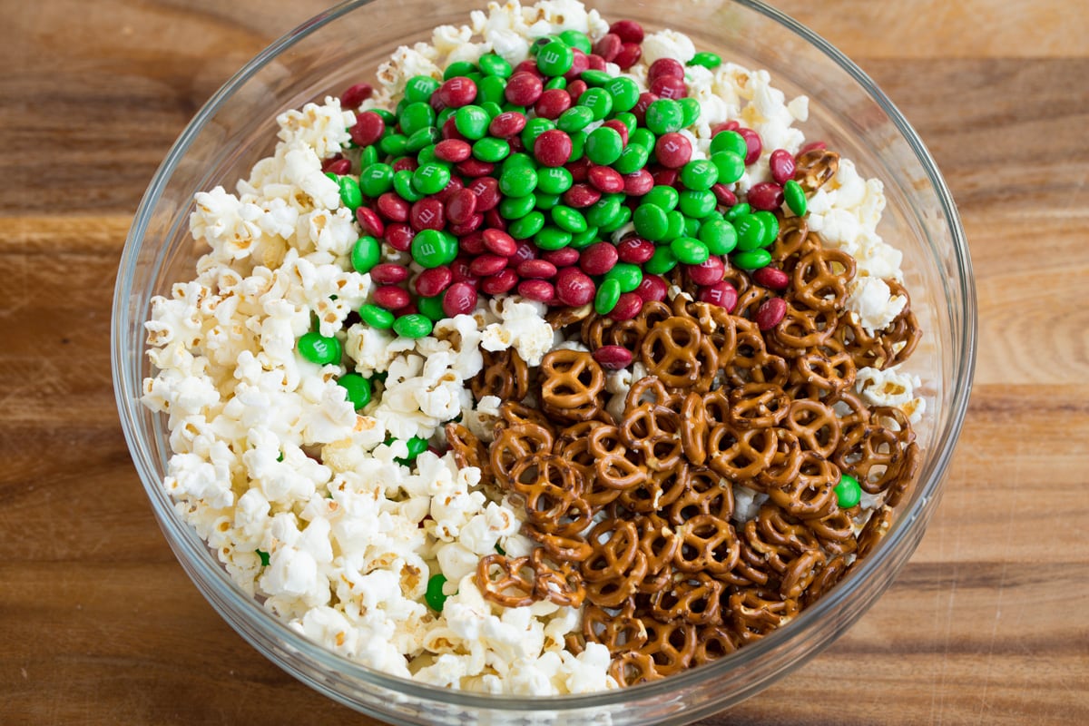 Christmas Crunch Adding pretzels and red and green m & m's to popcorn in bowl.