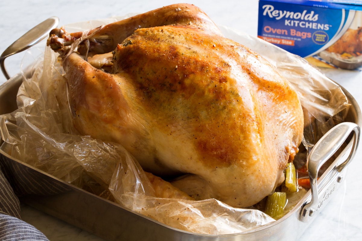 How to Cook Juicy Turkey in Oven Bag Turkey shown after cooking sitting in a roasting pan.