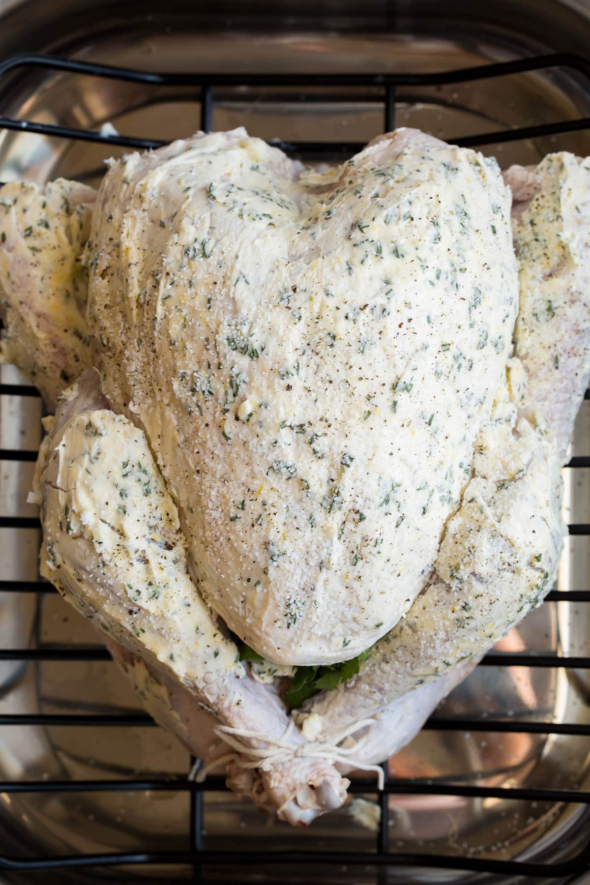 Roast Turkey - easy to follow recipe that turns out tender, juicy and full of flavor! A holiday staple! #turkey #thanksigiving Overhead image of whole turkey in a roasting dish on a roasting rack before baking.