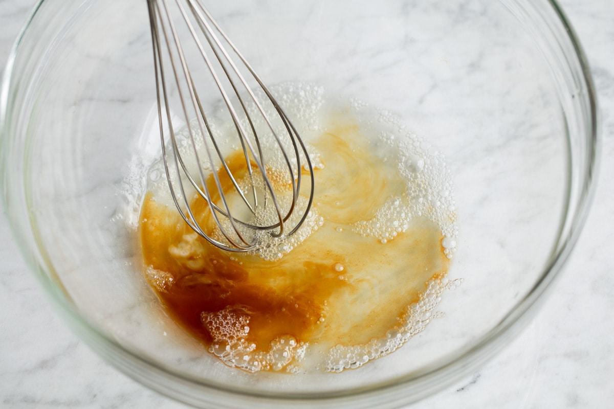 Candied Pecans Mixing egg white and vanilla extract with a whisk in a glass bowl.