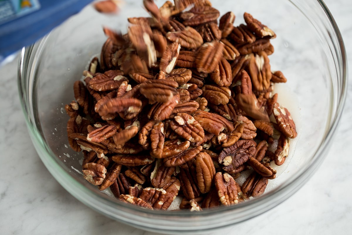 Candied Pecans Pouring pecans into glass mixing bowl.