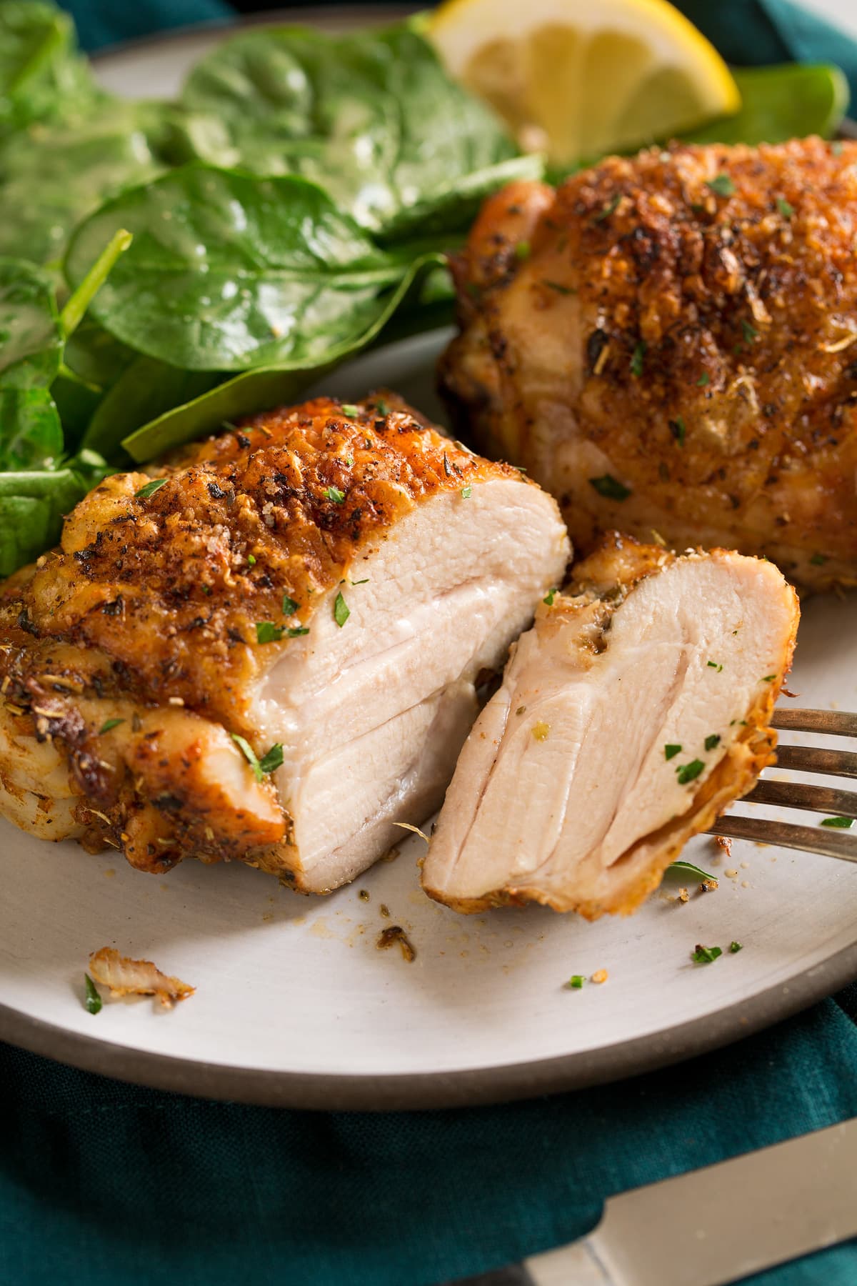 Baked Chicken Thighs Baked chicken thigh sliced into on a serving plate.