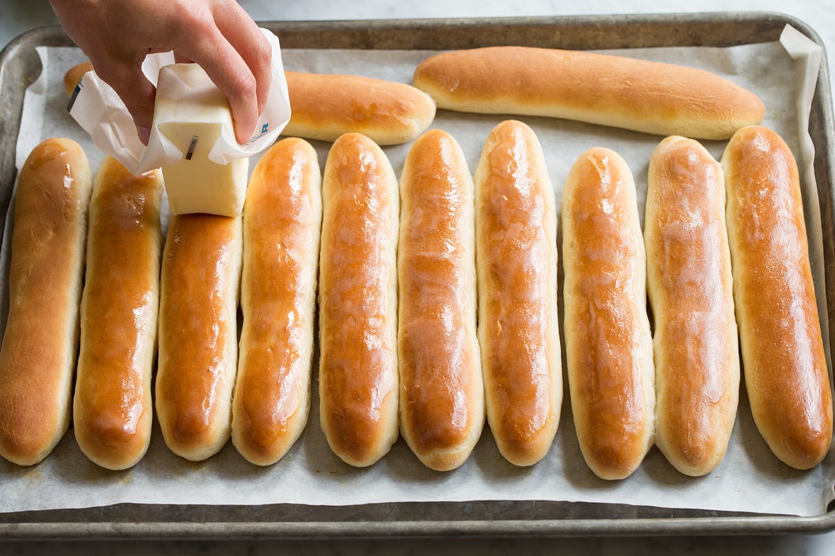 Breadsticks Recipe Buttering breadsticks on a baking sheet with a stick of butter.
