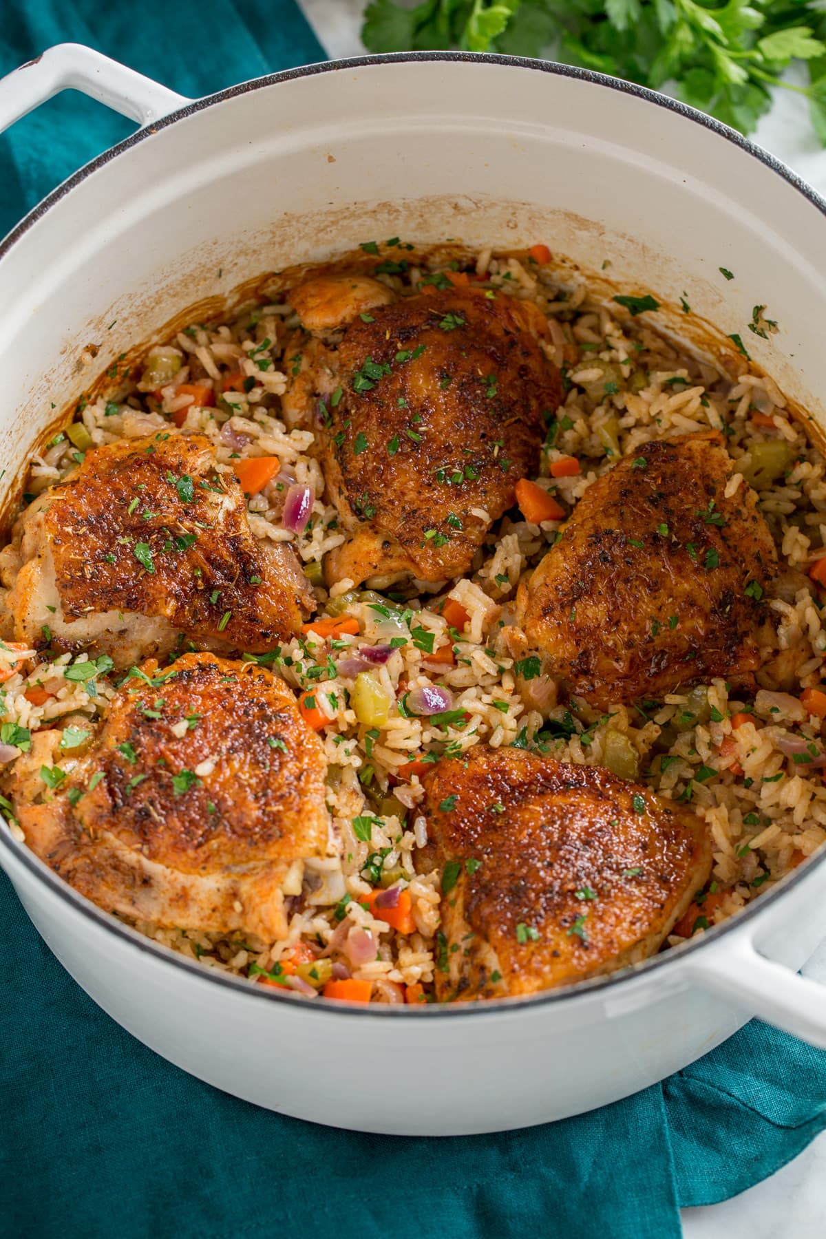 One Pot Chicken and Rice Chicken and rice in a white pot set over a turquoise cloth.