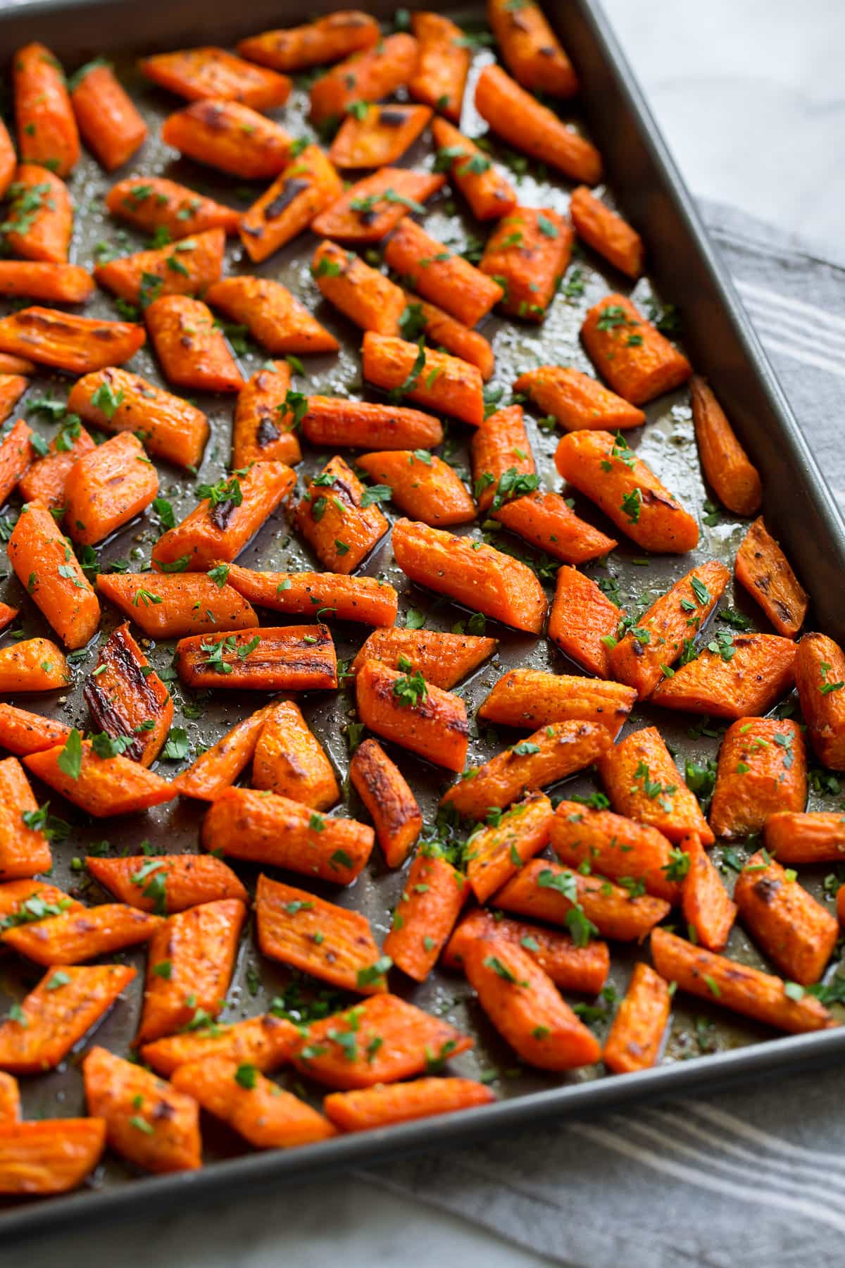 Honey Roasted Carrots Photo: Roasted carrots shown from the side on a dark baking sheet.