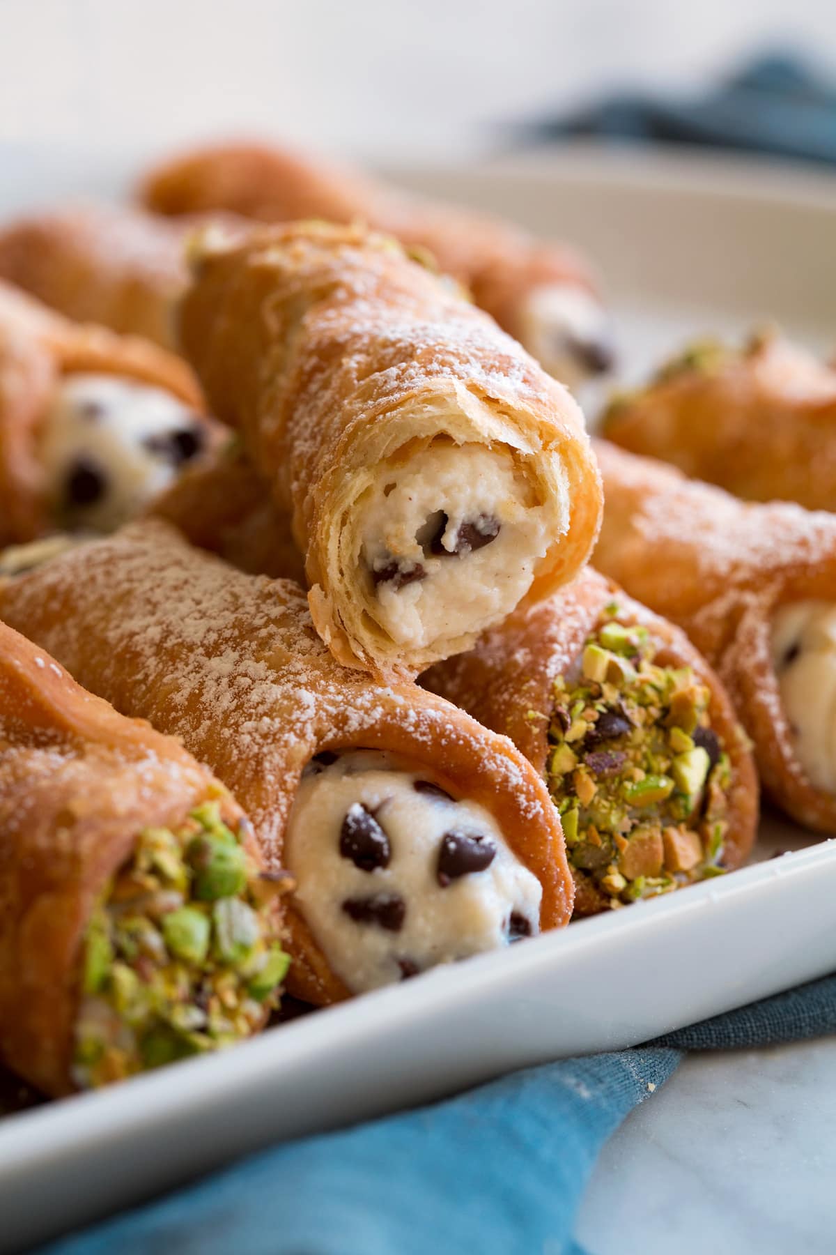 Cannoli Recipe Cannoli bitten into to show flaky layers and crispy texture along with ricotta and chocolate chip filling.