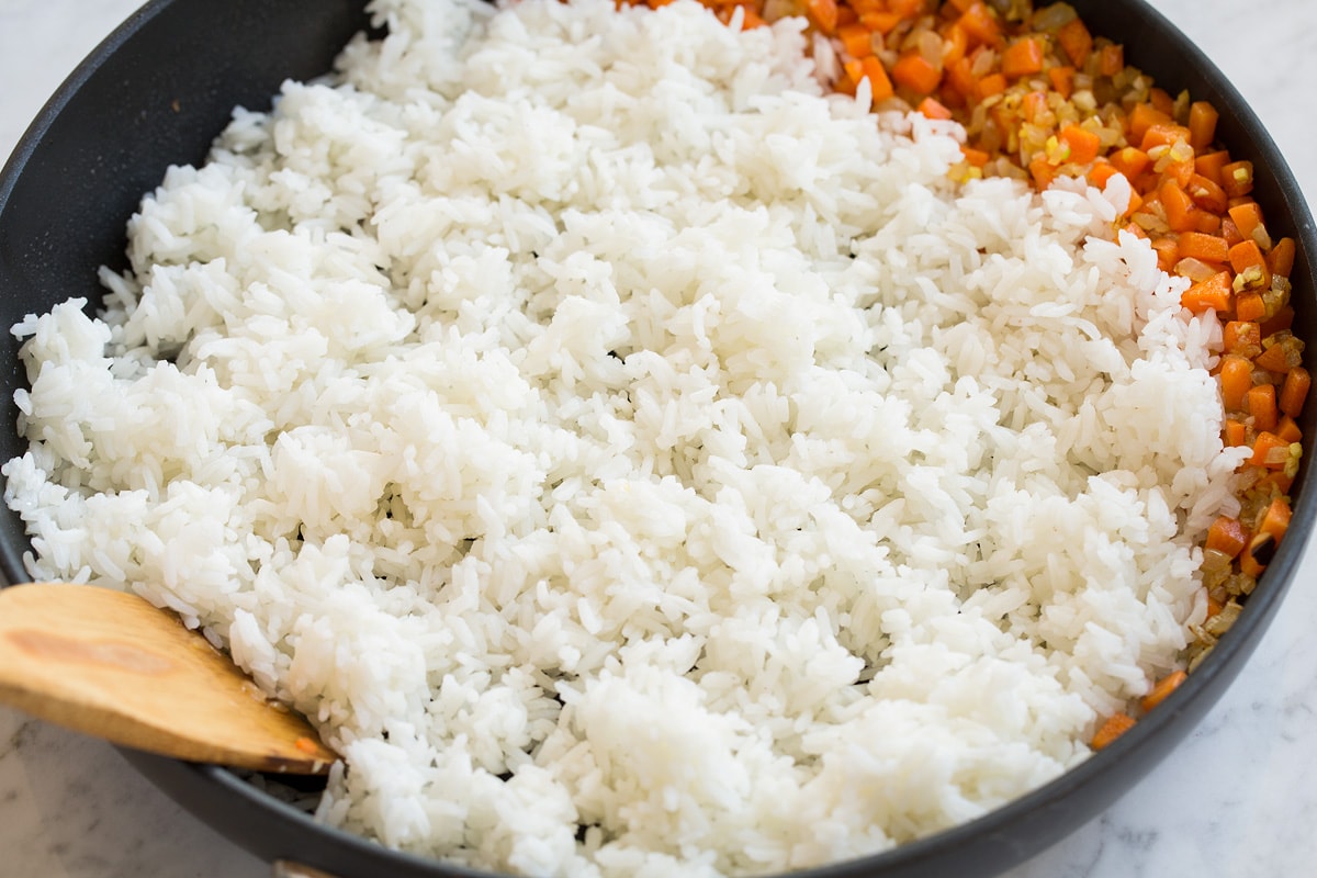 Fried Rice Frying white rice in a skillet with vegetables.