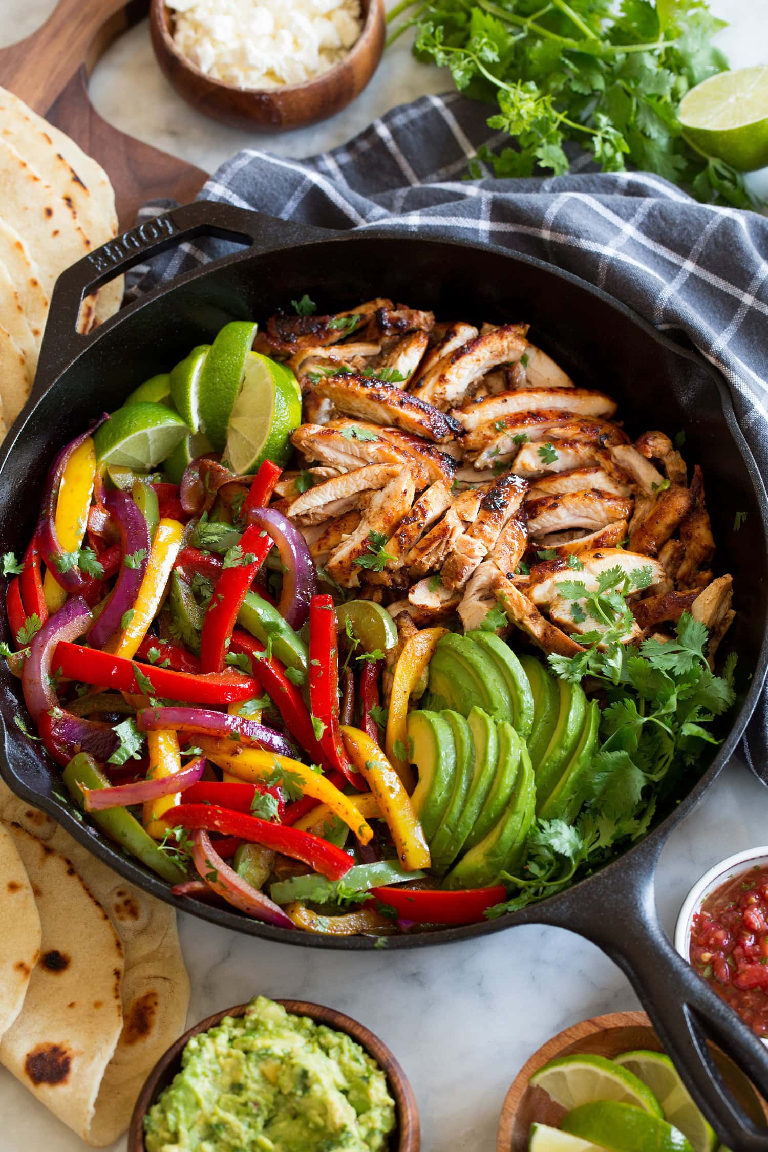 Chicken Fajitas Chicken and bell peppers in a cast iron skillet with cilantro, avocado and limes.