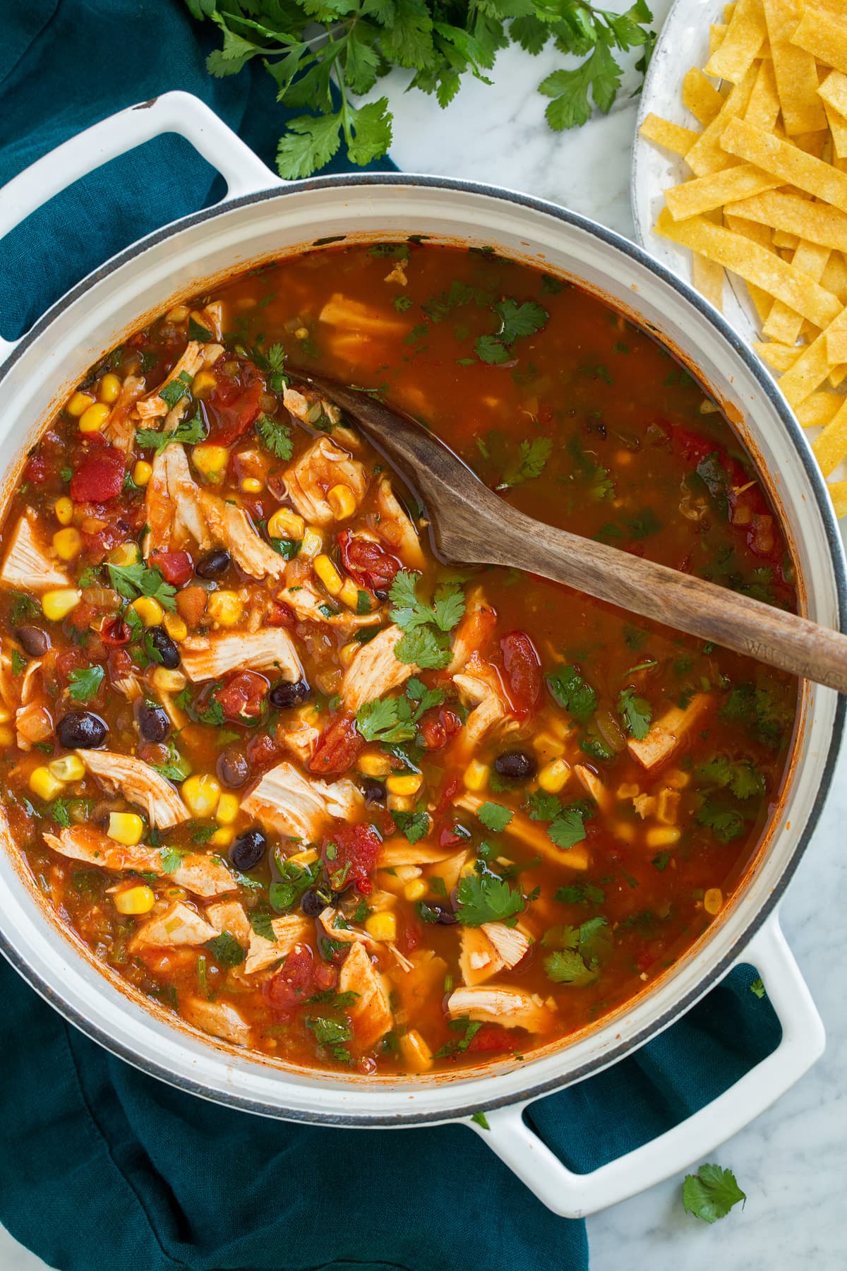 Chicken Tortilla Soup Chicken Tortilla Soup shown overhead in a large white pot, with corn tortilla strips on the side.