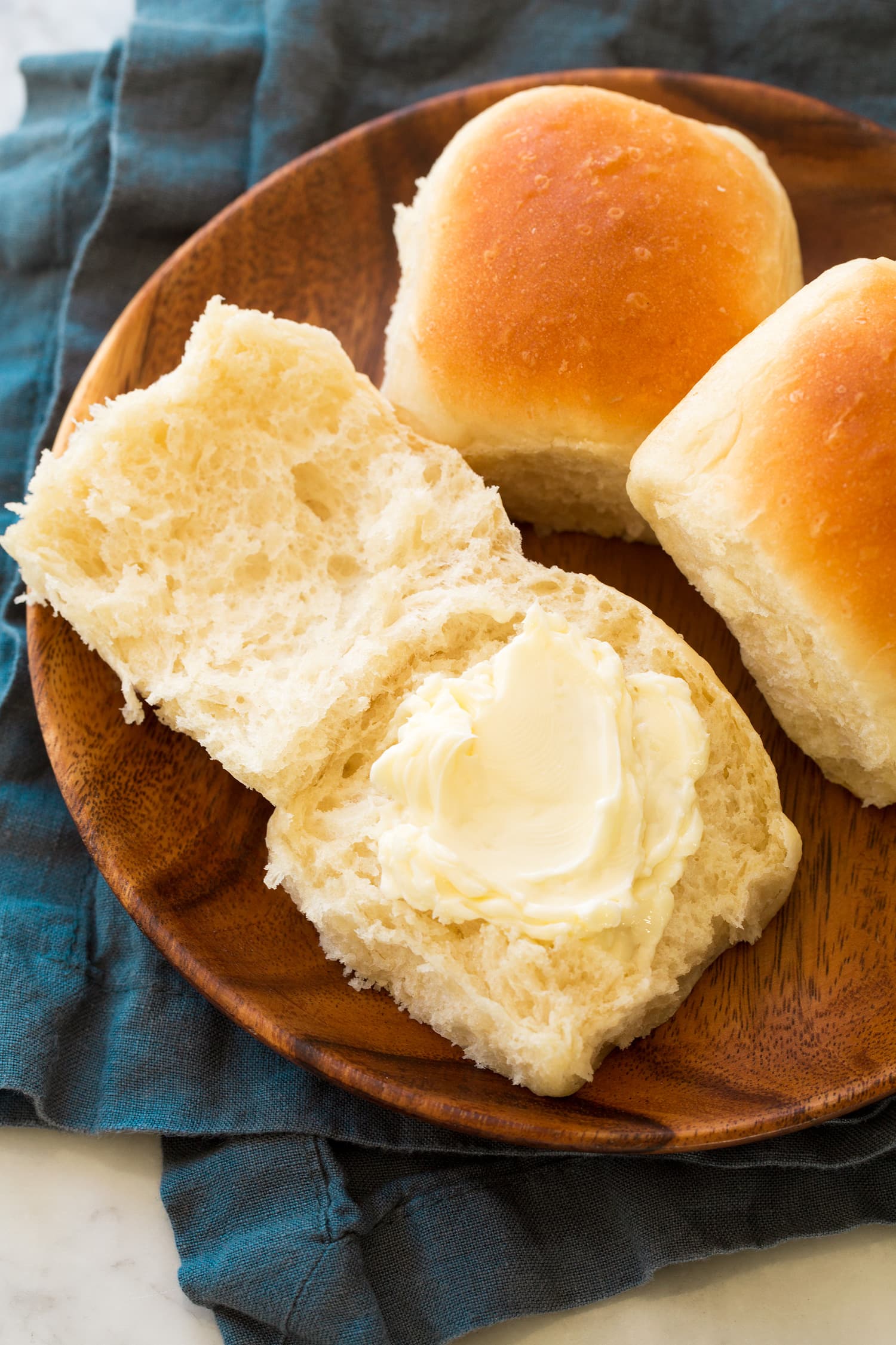 One Hour Dinner Rolls Roll sliced in half topped with butter.