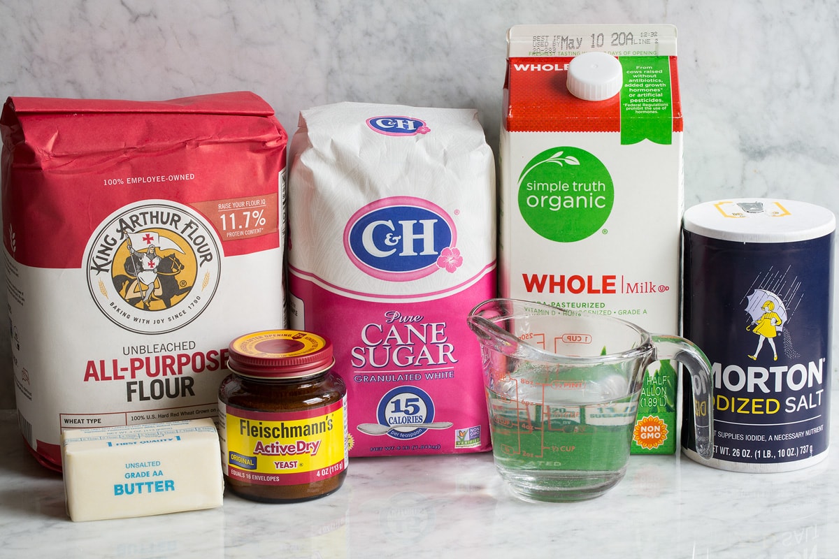 Homemade White Bread Recipe Image of ingredients used to make white bread. Includes all-purpose flour, sugar, milk, salt, water, yeast and butter.