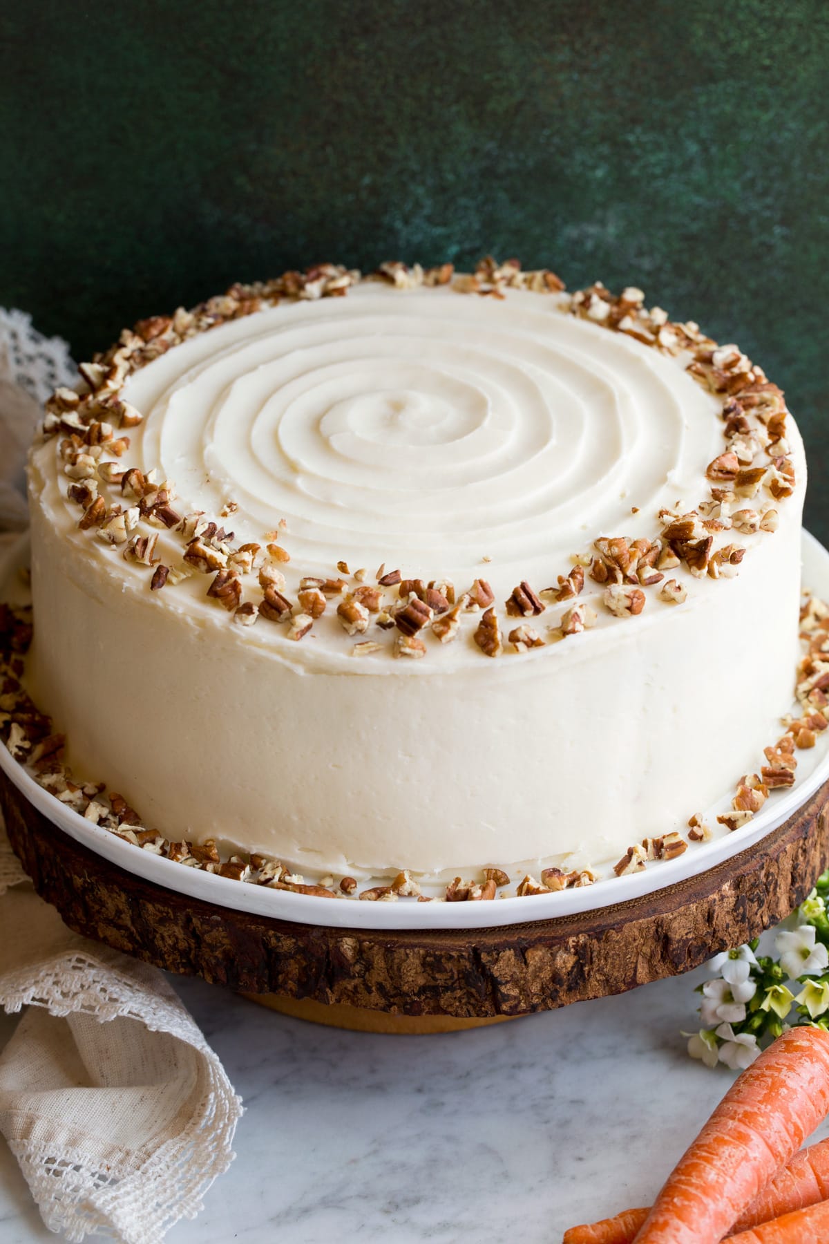 Best Ever Carrot Cake Whole carrot cake sitting on a wooden cake stand.
