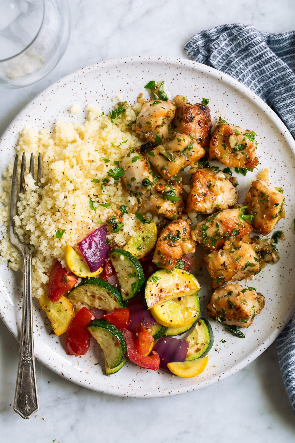 Garlic Butter Chicken Bites Garlic butter chicken bites on a plate with a side of couscous and fresh sauteed vegetables.