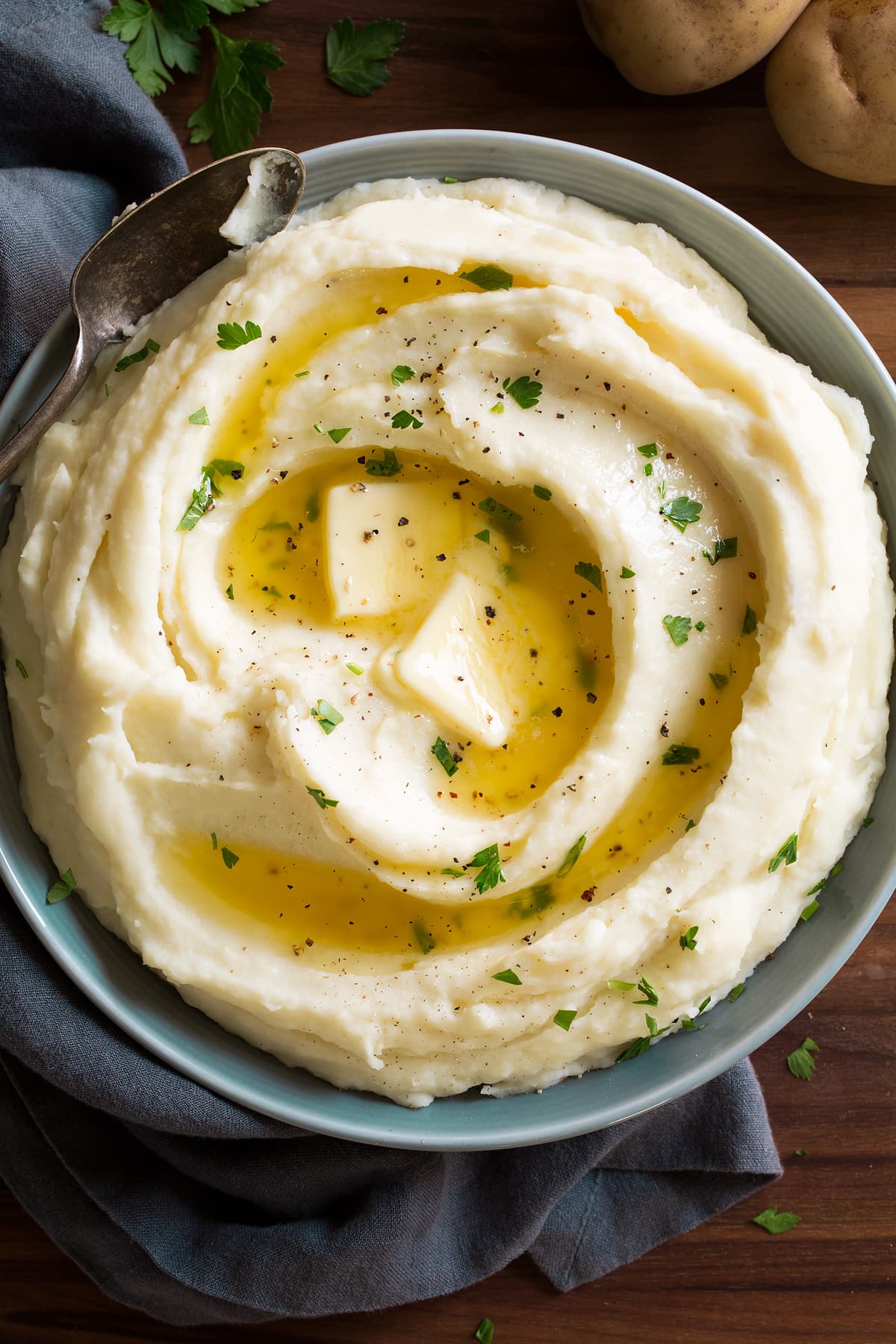 Mashed Potatoes Overhead image of mashed potatoes topped with butter in a grey bowl.