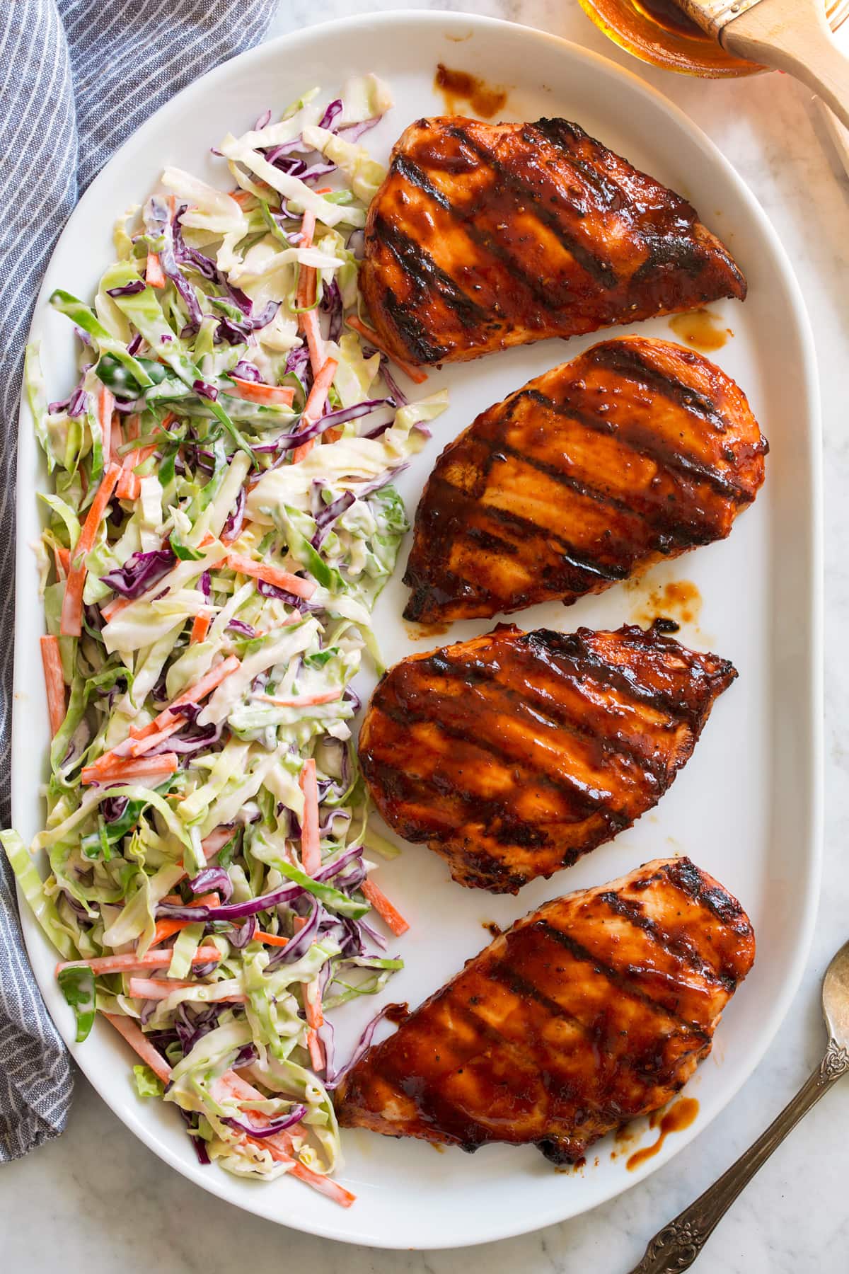 Homemade BBQ Sauce Overhead image of four grilled chicken breasts covered in bbq sauce on a platter with a side of coleslaw on the side of the platter.