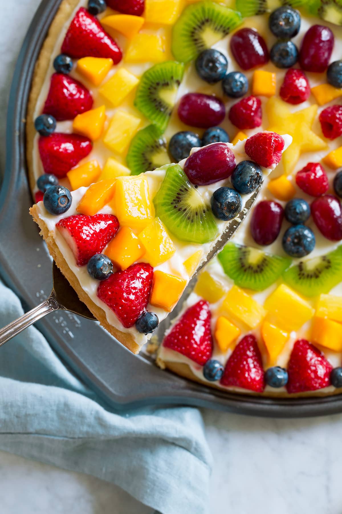 Fruit Pizza Overhead image of fruit pizza with slice cut and lifted out.