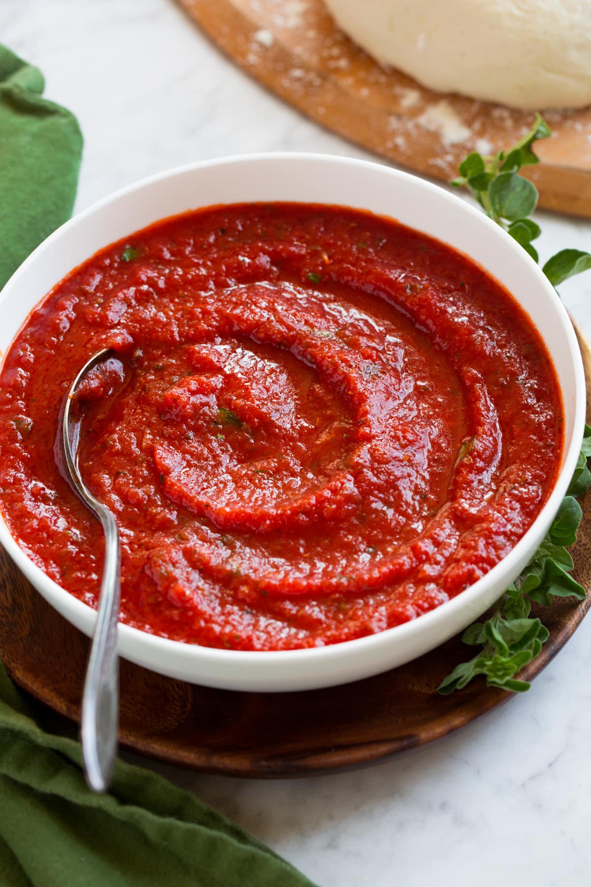 Homemade Pizza Sauce Homemade pizza sauce in a bowl with pizza dough in the background.