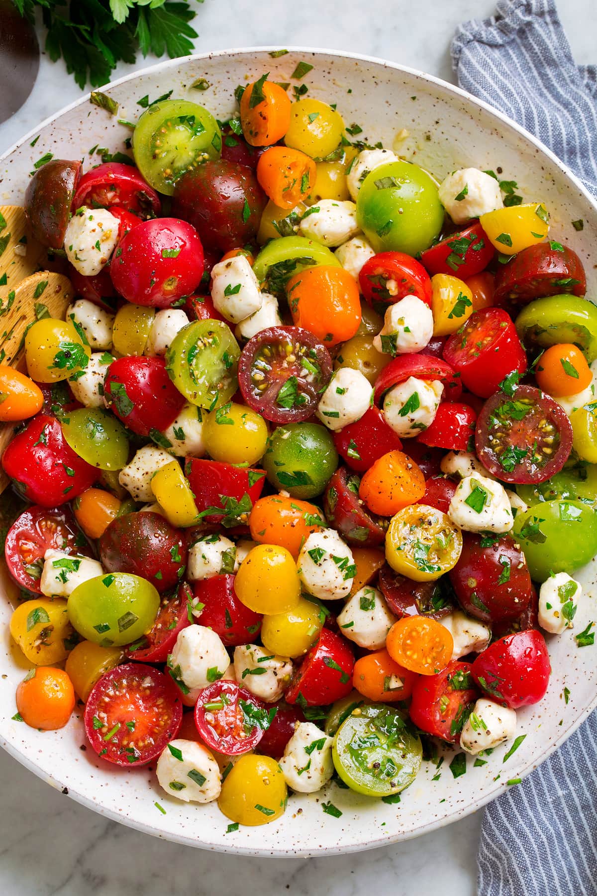 Tomato Salad Tomato Salad in a white serving bowl. Shown in salad are multi-color cherry tomatoes and grape tomatoes, mozzarella pearls and it's coated in a herb dressing.