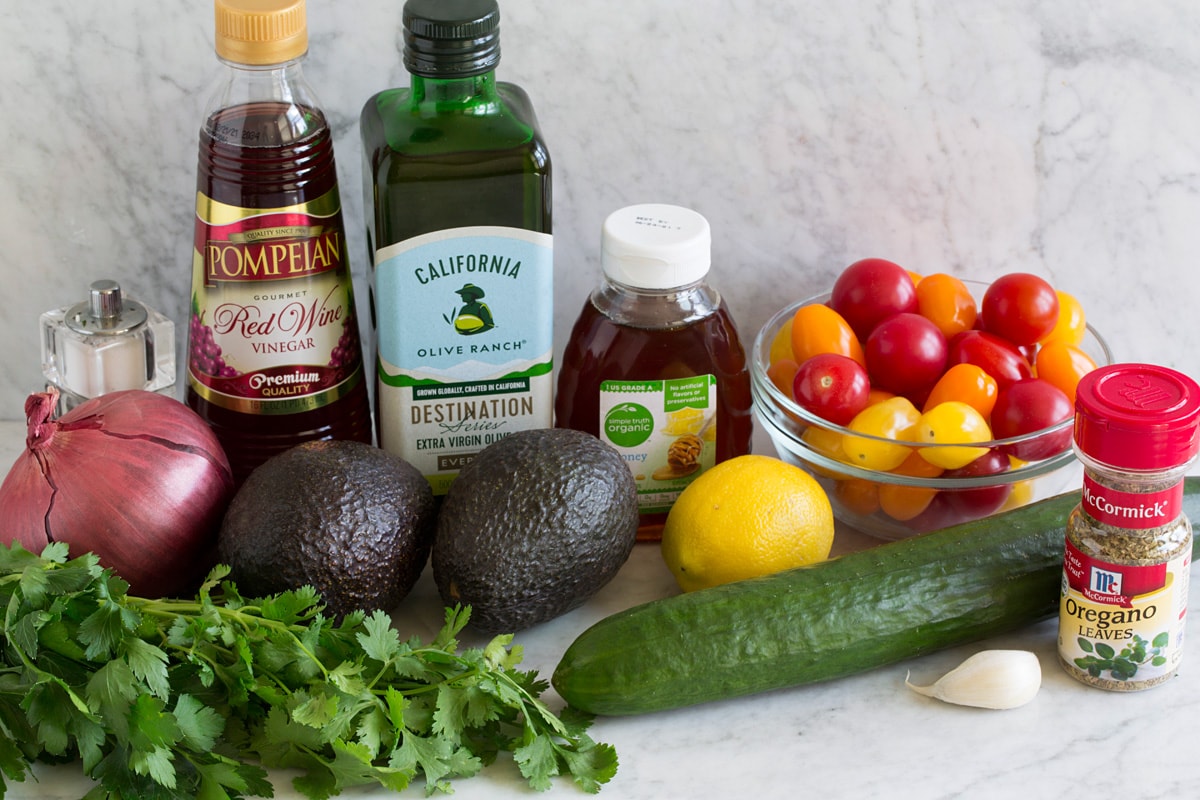 Avocado Salad Image of ingredients that go into avocado salad. Includes fresh avocados, red onio, cilantro, parsley, cucumber, garlic, lemons, grape tomatoes, honey, olive oil, red wine vinegar and oregano.