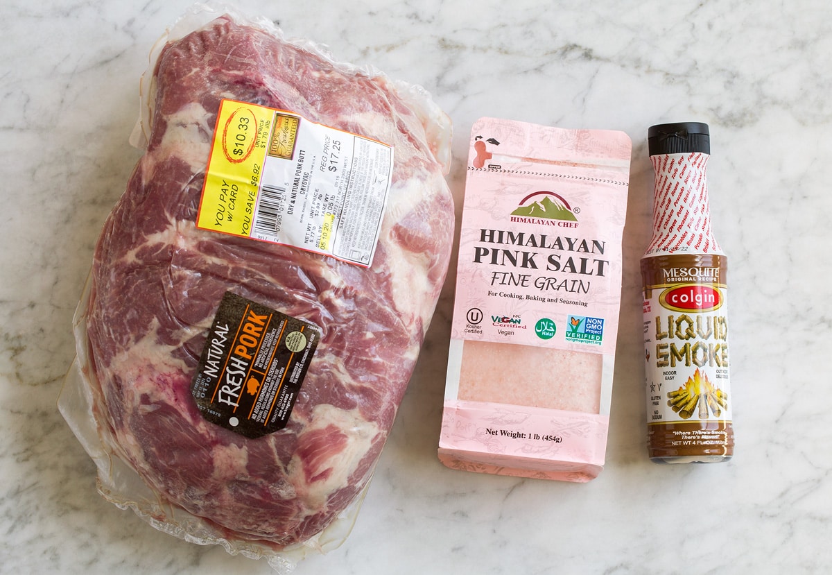 Kalua Pork Image of ingredients used for kalua pork. Includes pork shoulder, pink salt, and liquid smoke.