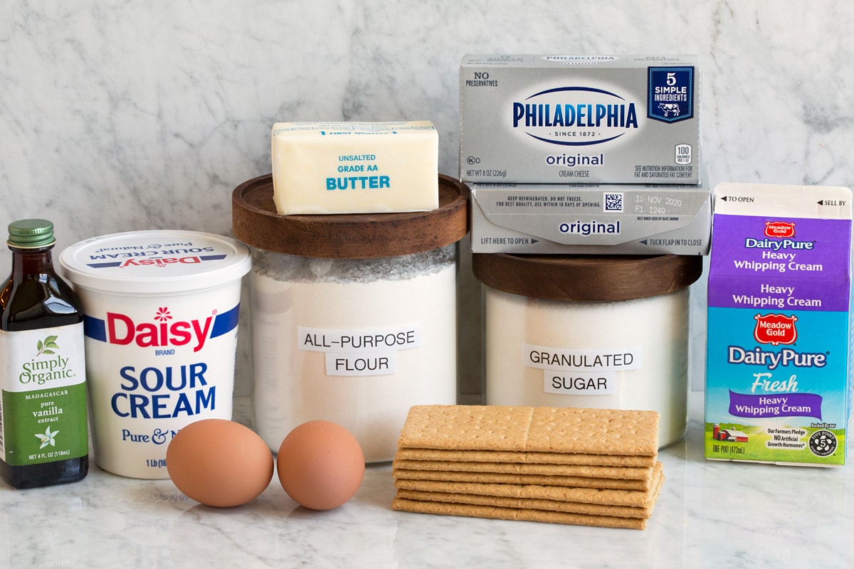 Mini Cheesecakes Image of ingredients used to make mini cheesecakes. Includes cream cheese, granulated sugar, all-purpose flour, eggs, graham crackers, sour cream, heavy cream, vanilla and butter.