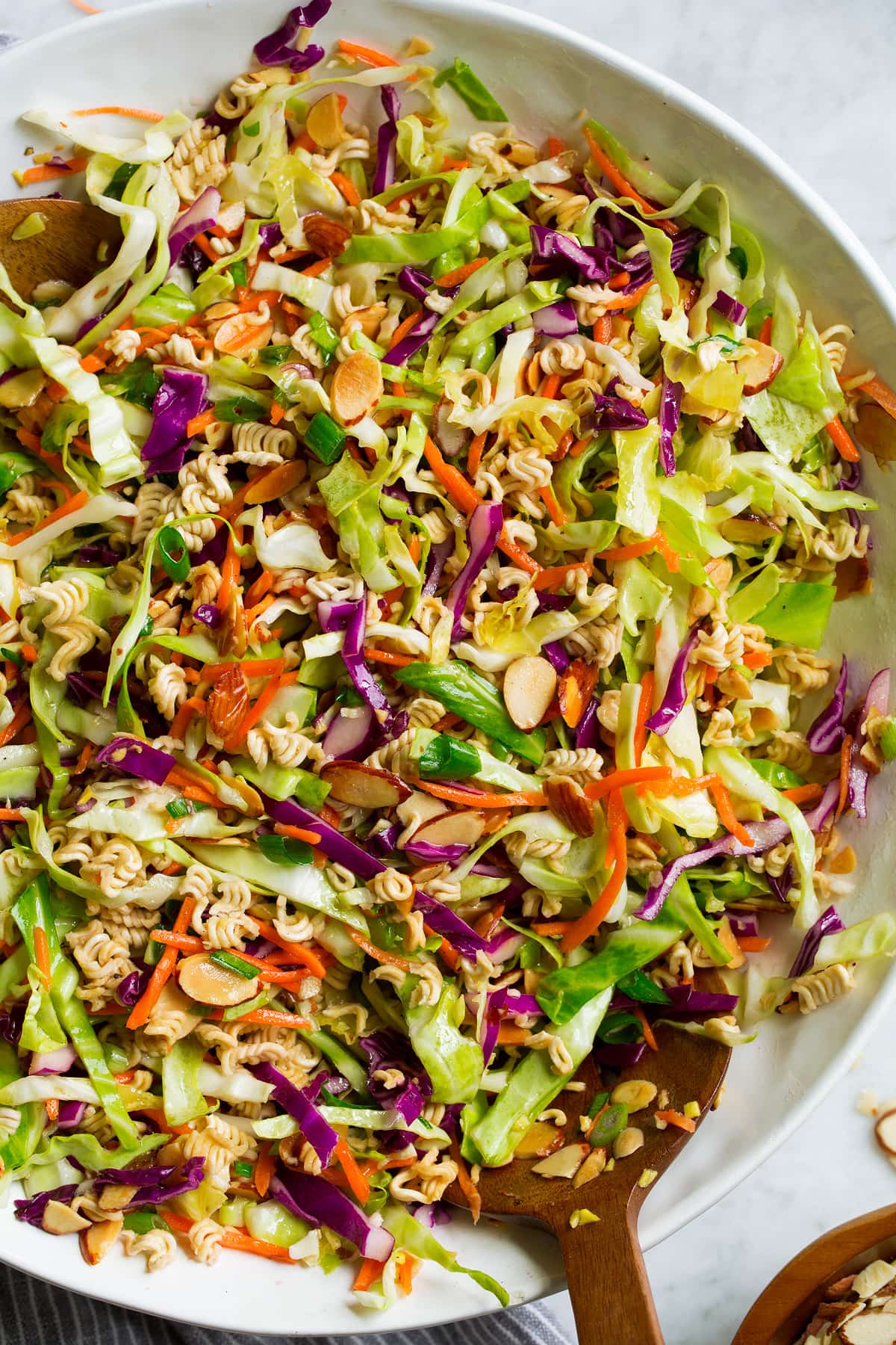 Close up overhead image of Asian ramen noodle salad in a large white salad bowl set over a marble surface. Close up overhead image of Asian ramen noodle salad in a large white salad bowl set over a marble surface.