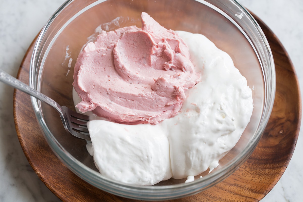 Easy Cream Cheese Fruit Dip Marshmallow fluff and strawberry fruit dip in a glass mixing bowl shown before blending.