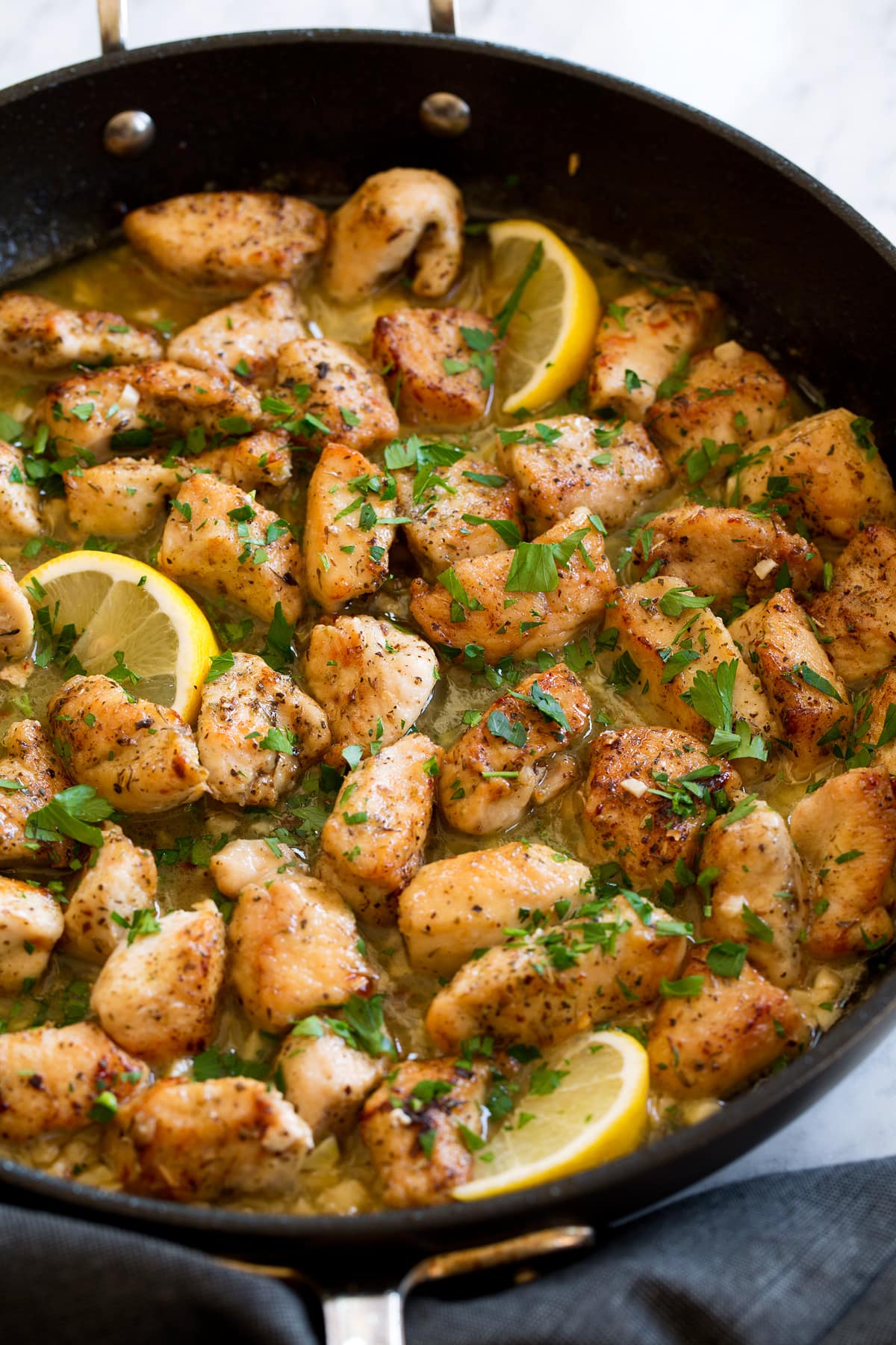 Chicken Scampi Chicken scampi with butter and wine shown in a dark skillet.
