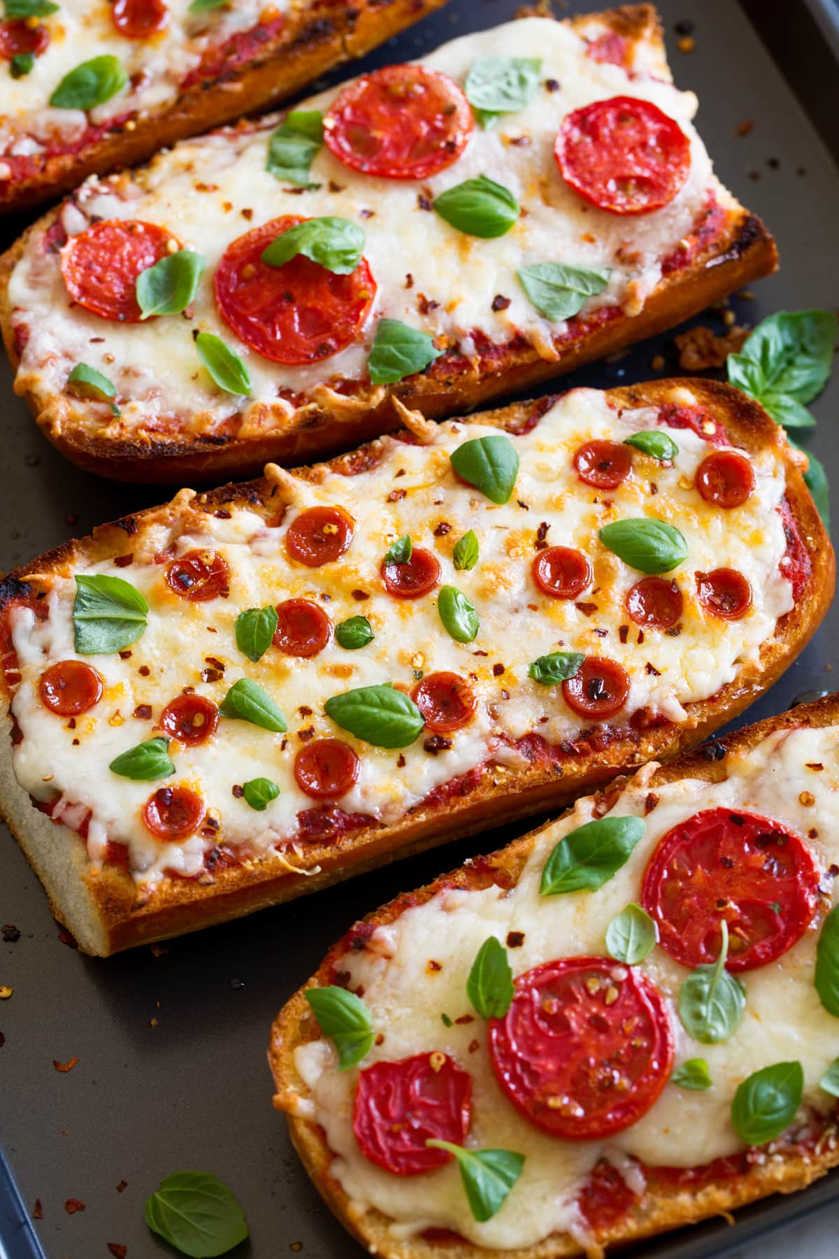 French Bread Pizza French Bread Pizza shown from a side angle on a baking sheet.