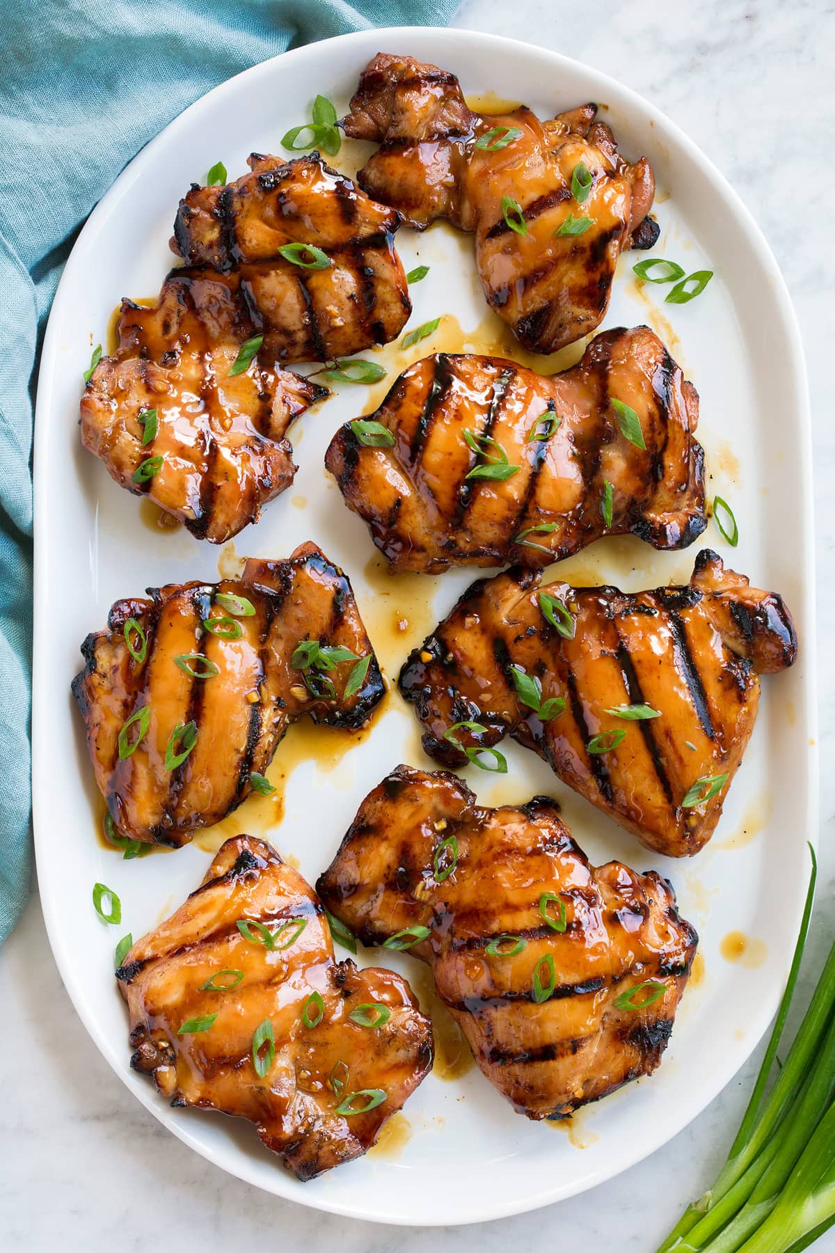 Grilled Marinated Teriyaki Chicken Marinated and grilled teriyaki chicken pieces on a white serving platter, shown overhead.