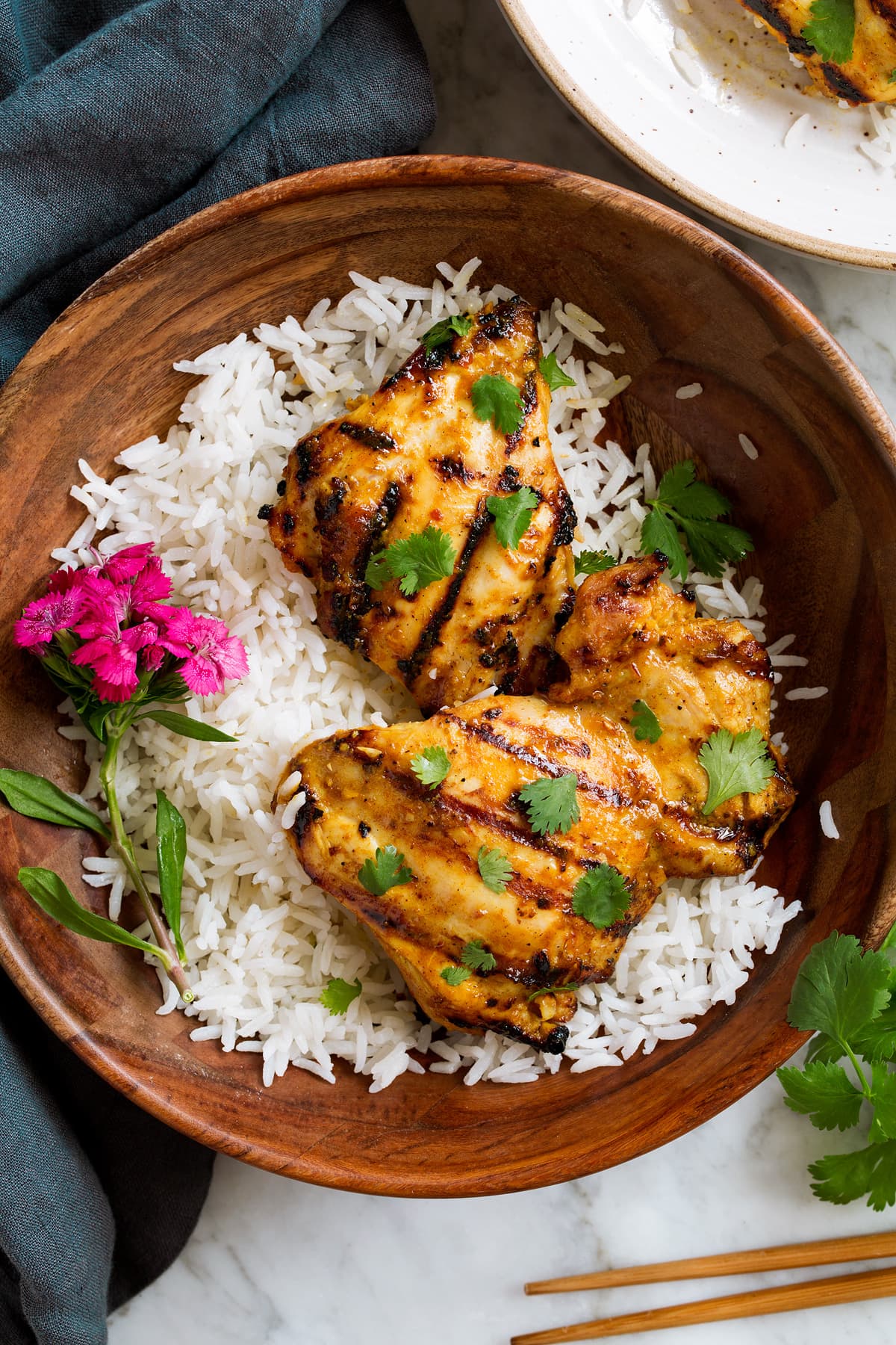 Thai Coconut Grilled Chicken Thighs Thai Coconut Grilled Chicken Thighs in a wooden serving bowl with rice and decorative flowers.