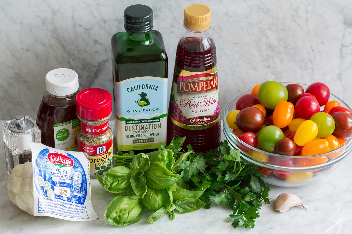Tomato Salad Image of ingredients used to make tomato salad. Includes cherry and grape tomatoes, fresh basil and parsley, garlic, fresh mozzarella, dried oregano, honey, olive oil, red wine vinegar and salt and pepper.