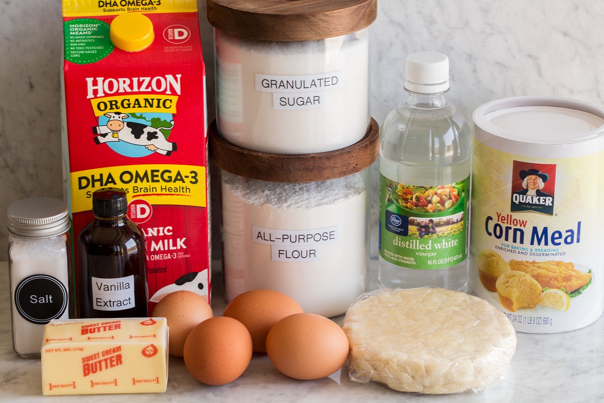 Chess Pie Image of ingredients used to make chess pie. Includes pie crust dough, cornmeal, vinegar, eggs, sugar, flour, milk, vanilla, butter and salt.