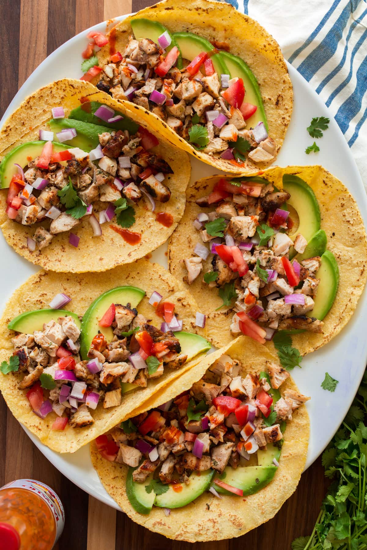 Homemade Corn Tortillas Image of tacos on a platter with homemade tortillas shown. They are topped with diced chicken, avocado, tomato, cilantro and onion.