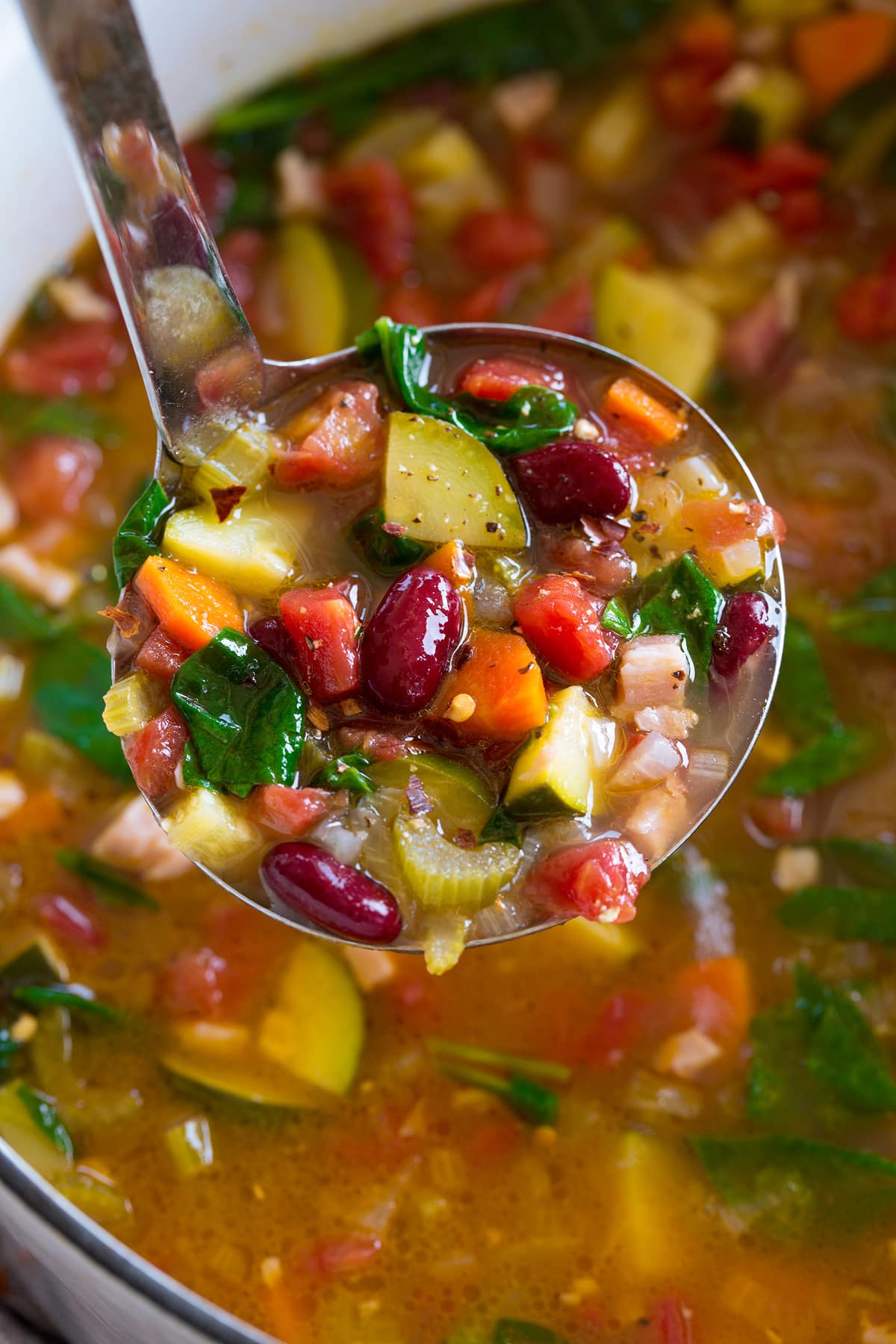 Minestrone Soup Image of ladle filled with minestrone soup shown close up.