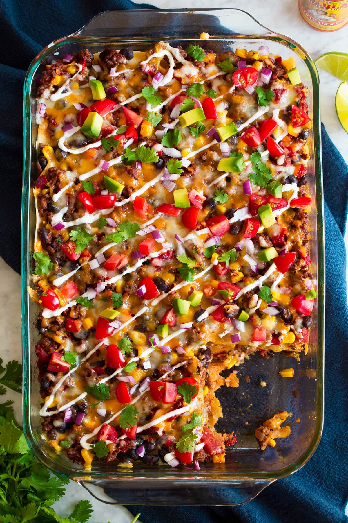 Taco Casserole Overhead image of taco casserole in glass baking dish set over a blue cloth.