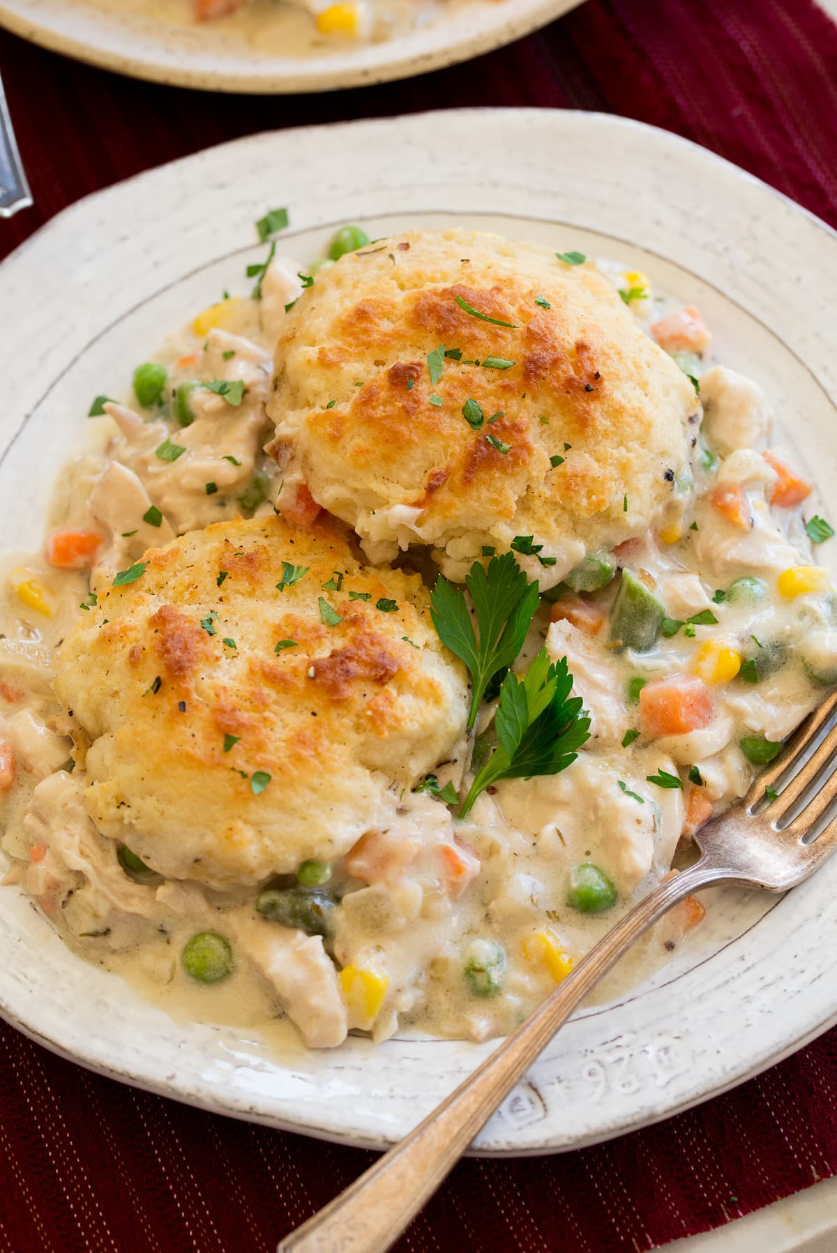 Chicken Pot Pie with Biscuits Serving of chicken and biscuit pot pie on a white plater with a fork to the side.
