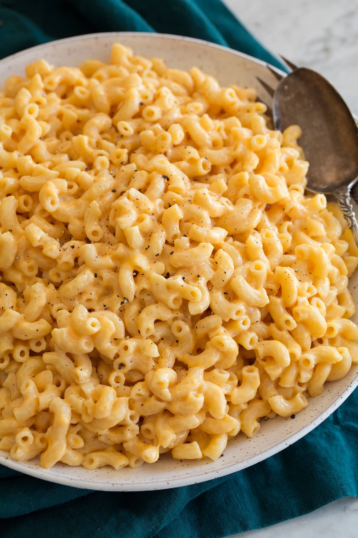 Instant Pot Macaroni and Cheese shown in a white serving bowl set over a turquoise napkin.