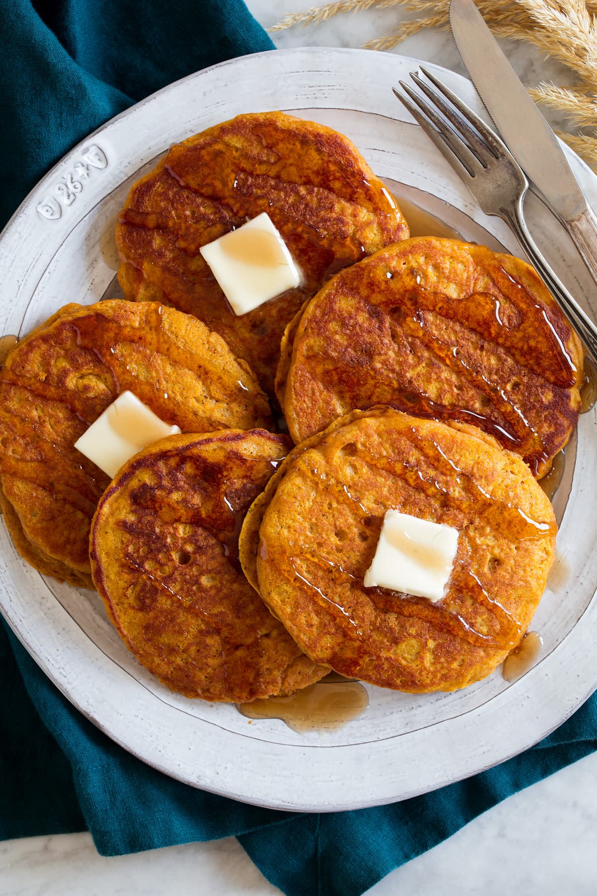 Pumpkin Pancakes Overhead image of pumpkin pancakes overlapping on a large white plate.