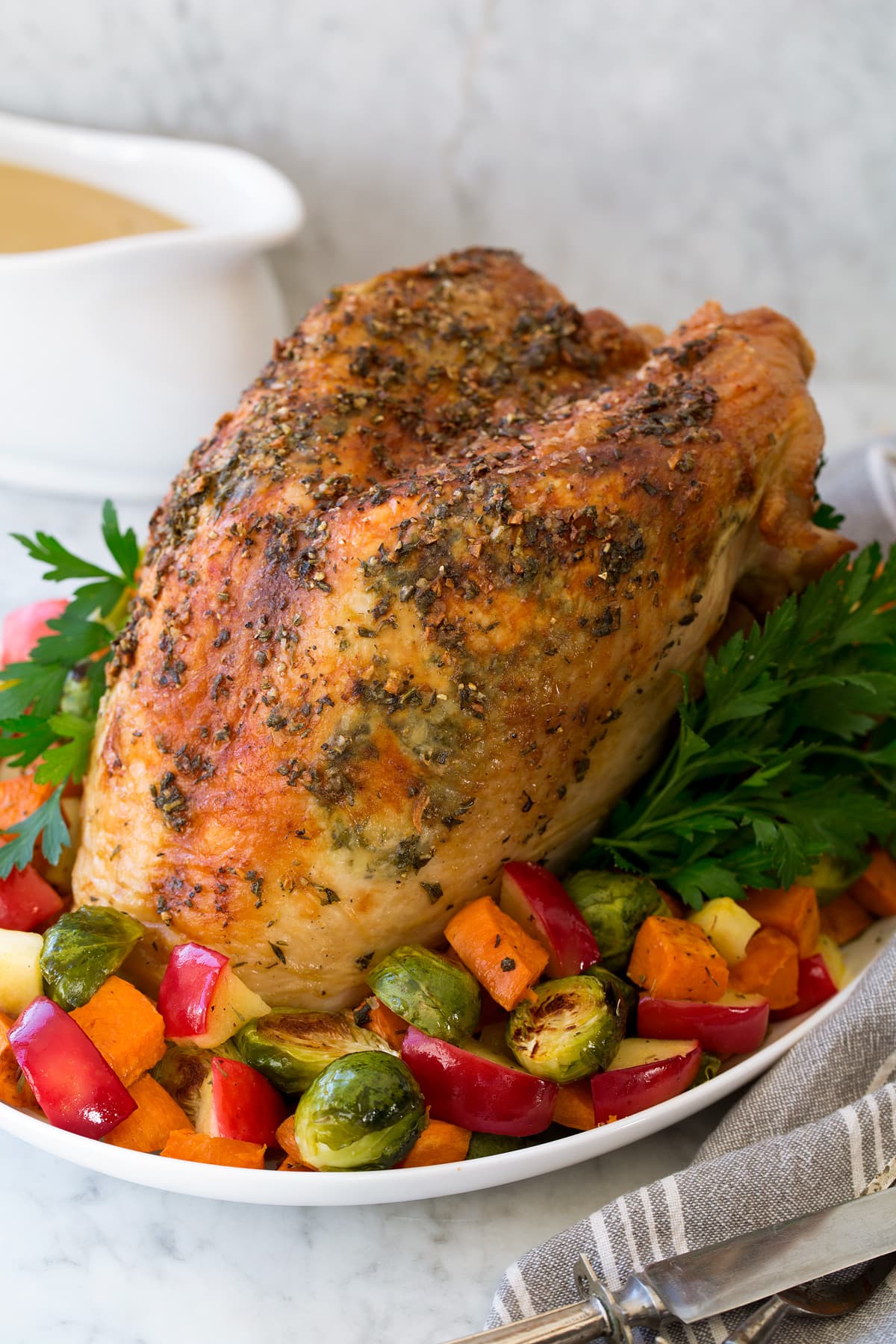 Roast Turkey Breast A whole Roast Turkey Breast shown on a platter with roasted vegetables and herbs.