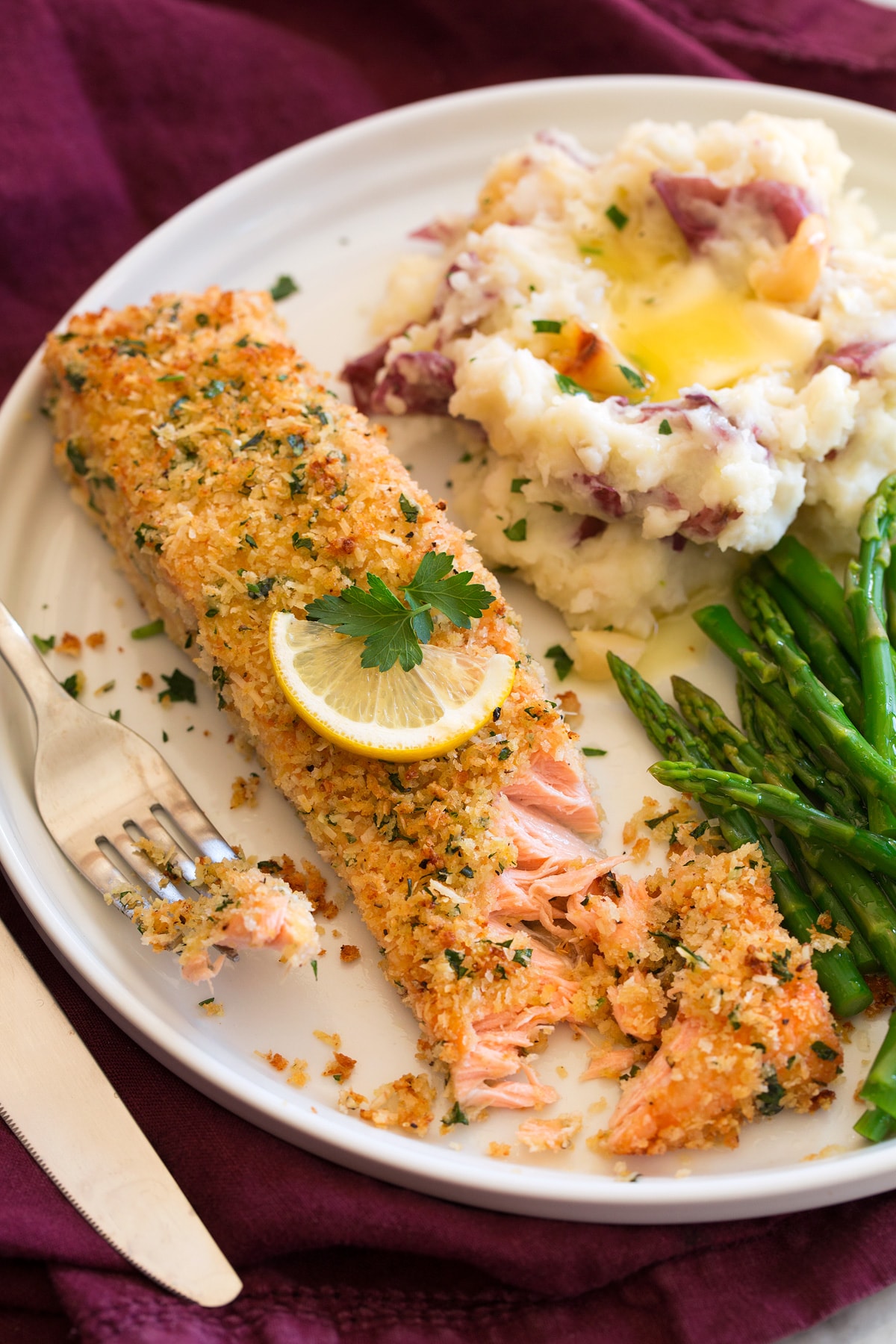 Baked Parmesan Crusted Salmon Baked salmon with parmesan and panko breadcrumb coating shown served on a plater with asparagus and garlic mashed potatoes.